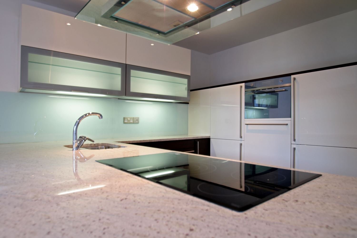 Modern kitchen with a beige countertop, an electric cooktop, a stainless steel sink, and white and gray cabinetry.