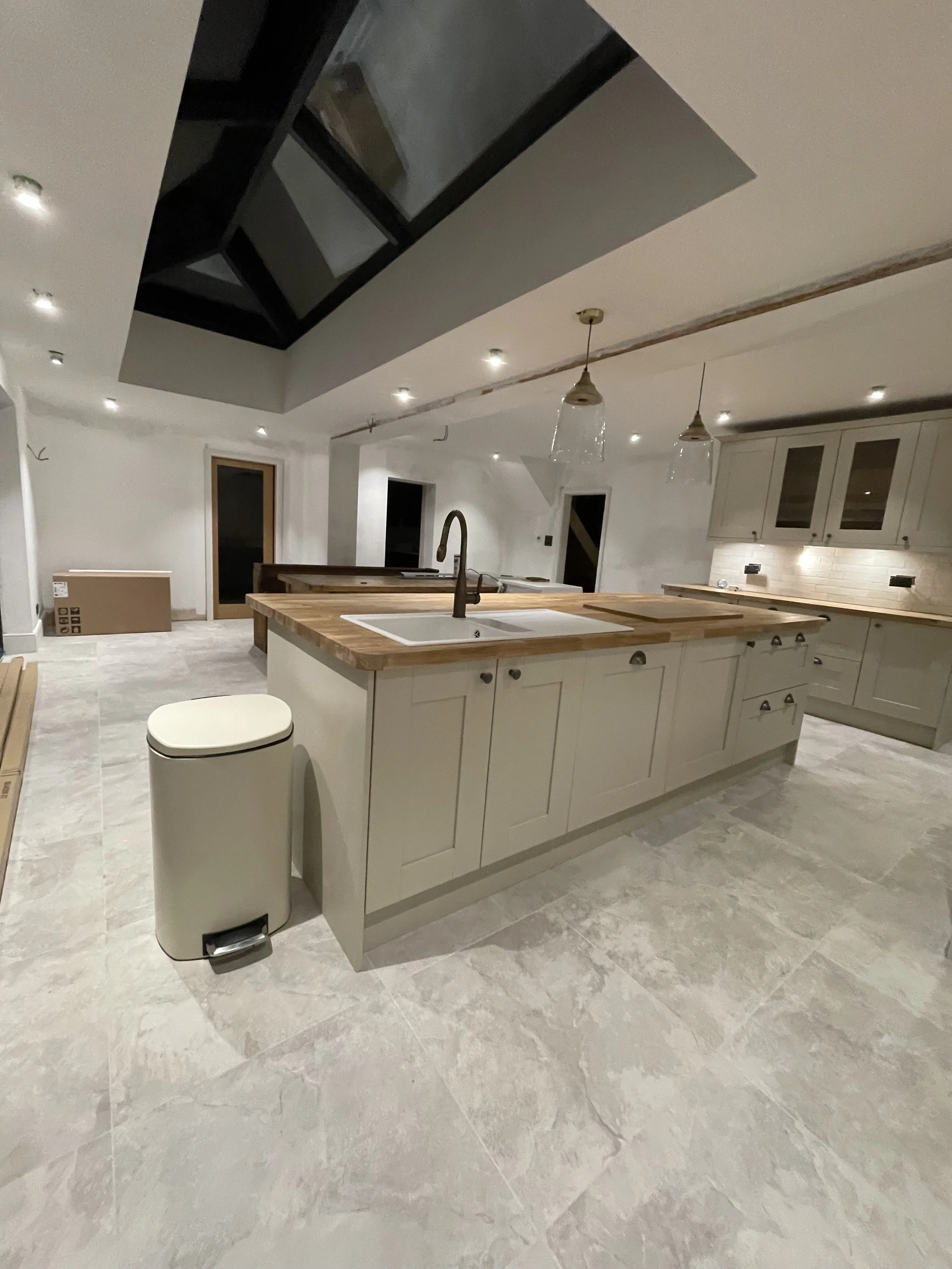 Modern kitchen with an island, pendant lights, beige cabinet, and a sloped ceiling with skylight.
