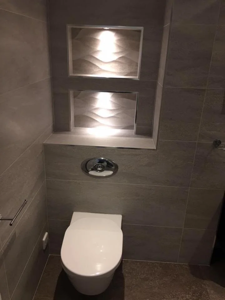 Modern toilet with wall-mounted flush system and decorative wall tiles featuring an abstract wave pattern.