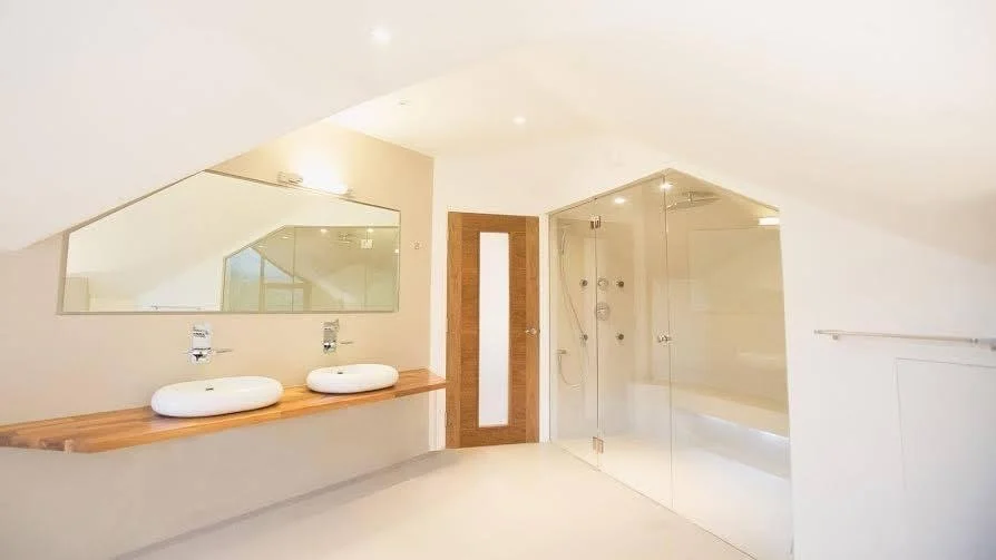 Modern bathroom with dual sinks, large mirror, glass shower enclosure, and minimalistic decor.