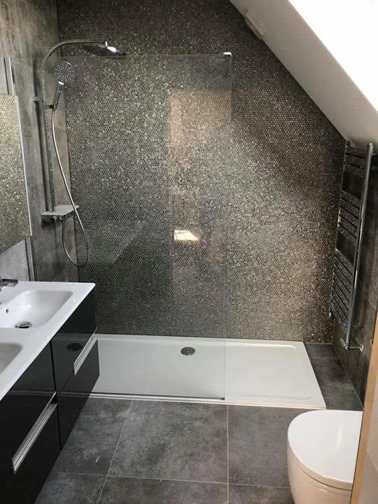 Modern bathroom with a walk-in shower, black vanity, gray tile floors, a white toilet, and a heated towel rack on the wall.