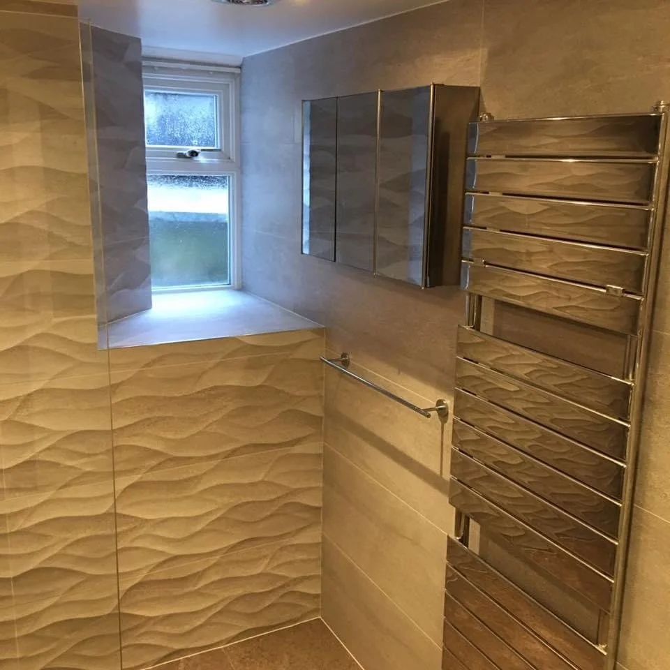 Modern bathroom with beige textured wall tiles, a frosted window, mirror cabinet, and heated towel rail.