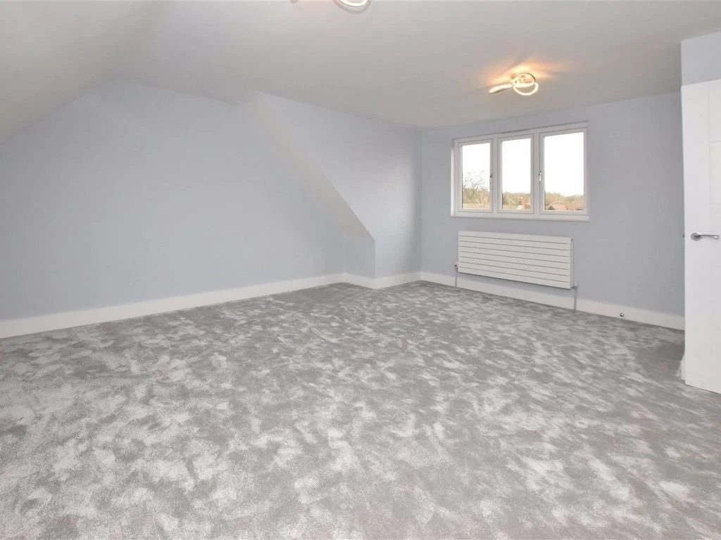 Empty room with light gray walls, carpeted floor, window, and door