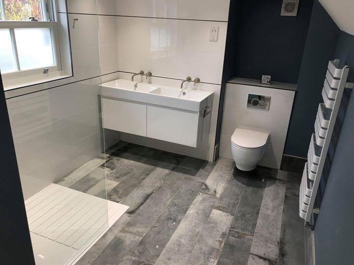 Modern bathroom with a window, white double sink, wall-mounted toilet, and a heated towel rack.