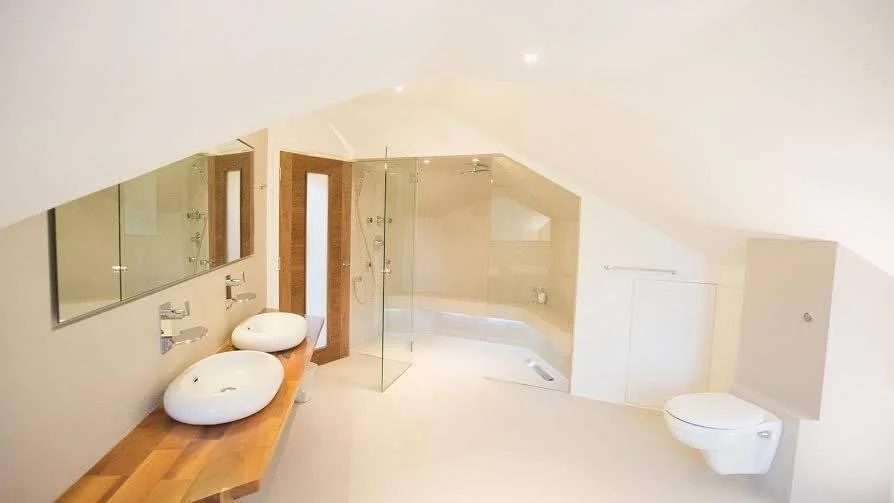Modern bathroom with two vessel sinks on a wooden countertop, a glass-enclosed shower, and a wall-mounted toilet.