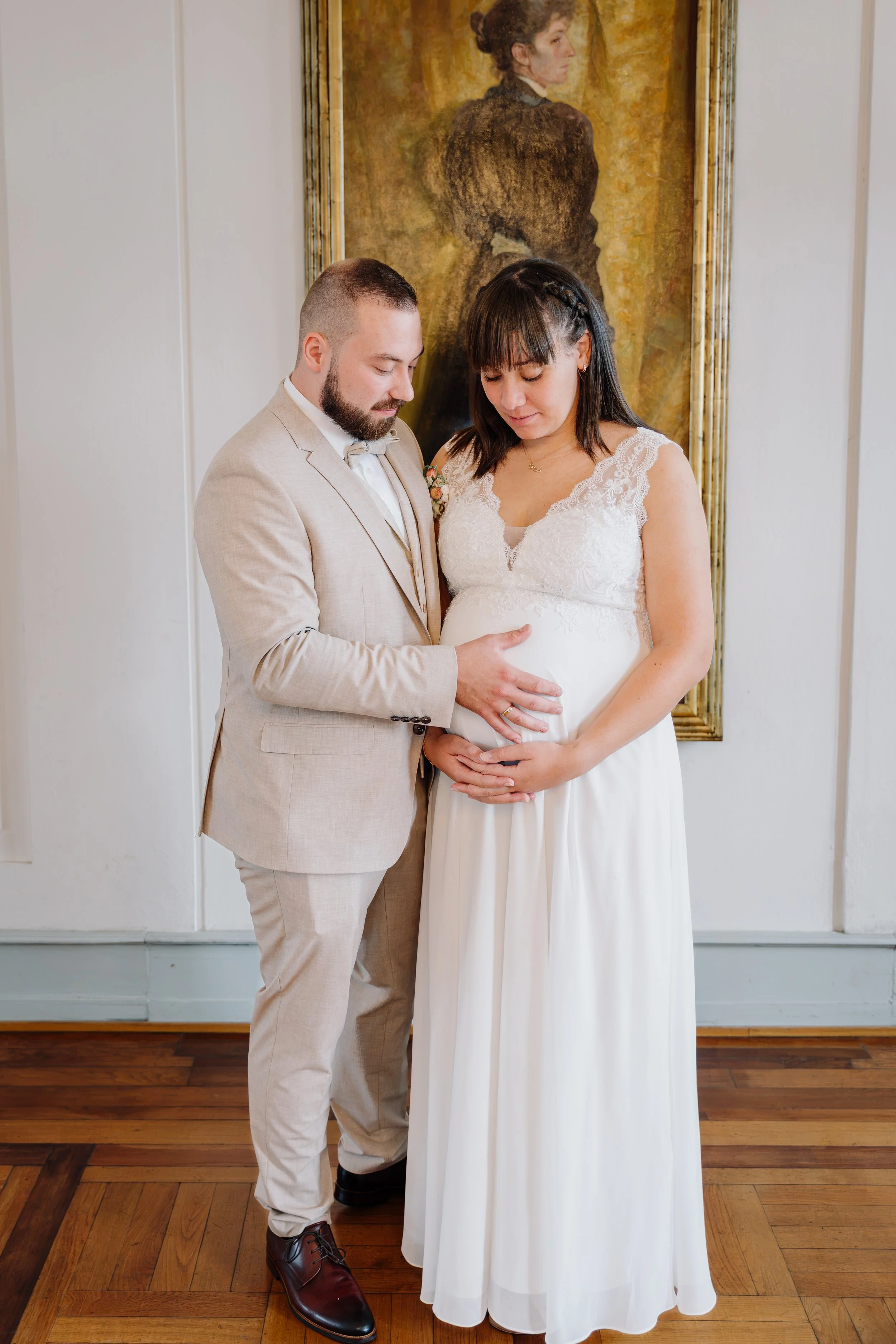 Brautpaar in Hochzeitkleidung vor einem gerahmten Porträtgemälde