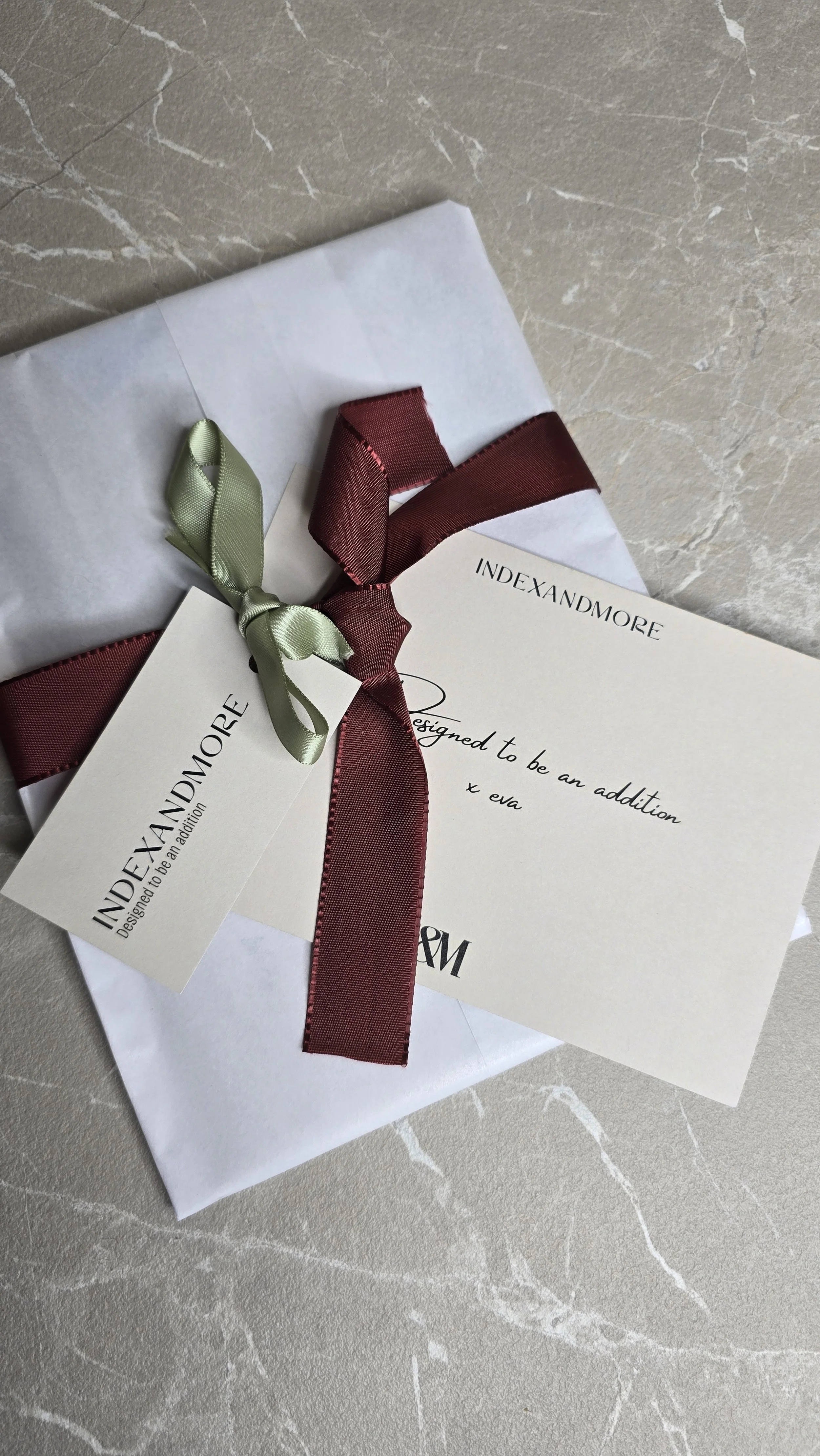 Een cadeaubon van Indexandmore met een rode en een groene strik.