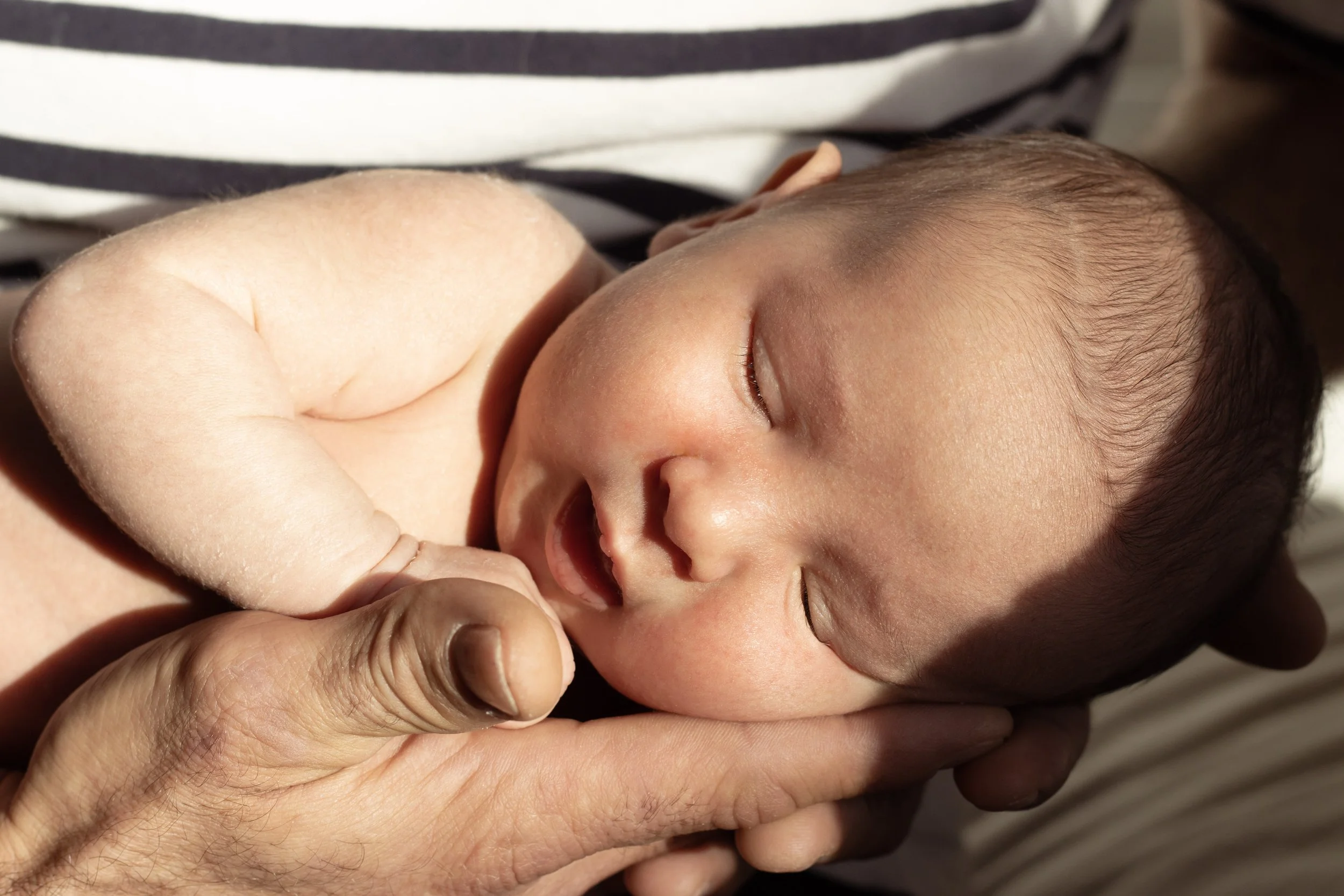 Un bébé endormi, tenu dans les bras d'une personne, montrant la paix et la sécurité.