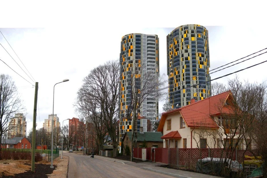 Two modern high-rise apartment buildings with a circular design, yellow and black patterned facades, are situated behind a traditional house with a red roof, on a residential street lined with leafless trees and power lines.