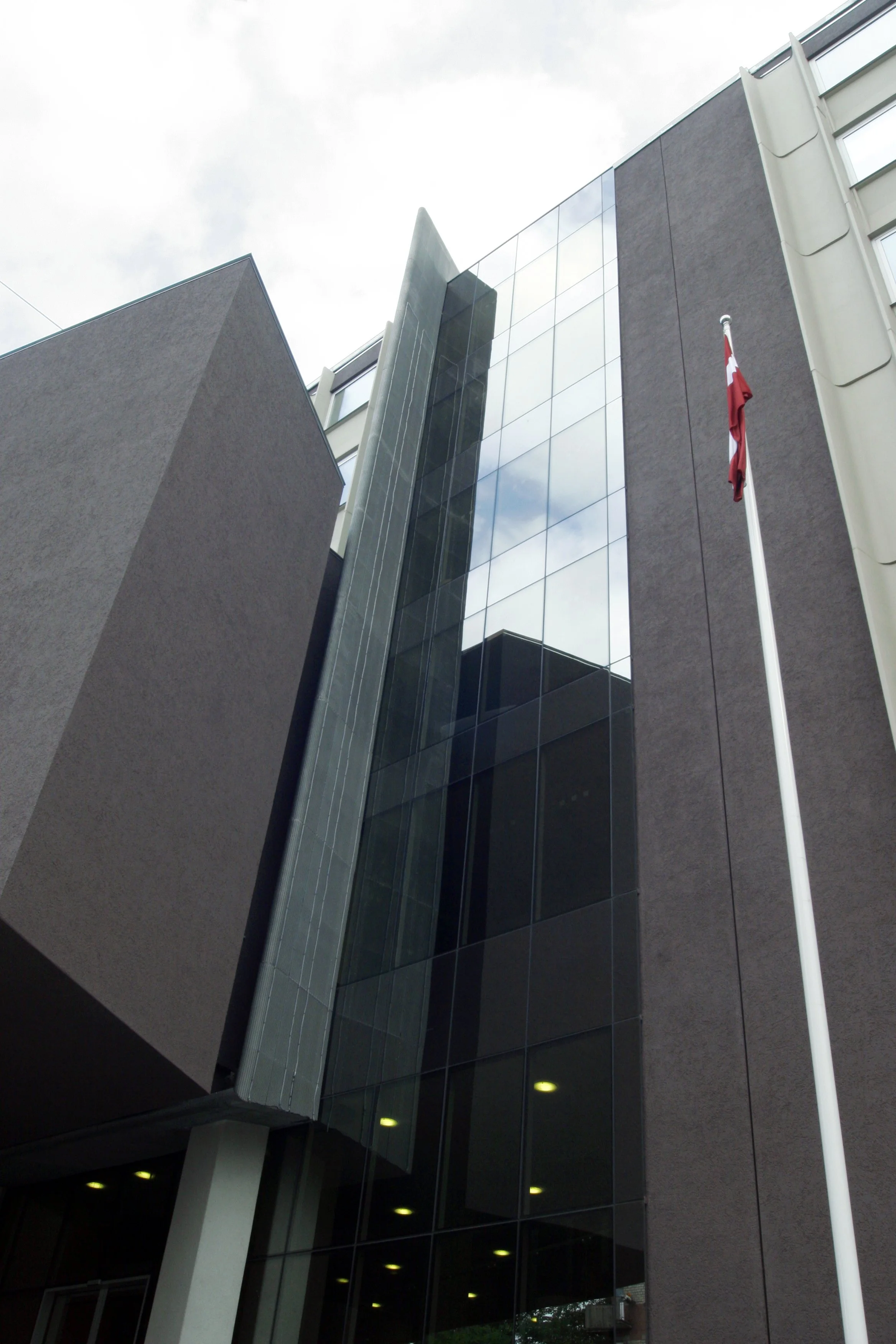 A modern building with reflective glass windows and a Canadian flag on a flagpole outside.
