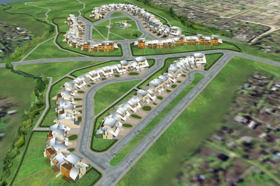 Aerial view of a modern housing development with curved streets, multiple townhouses with white roofs, and a central park area with green spaces and pathways.