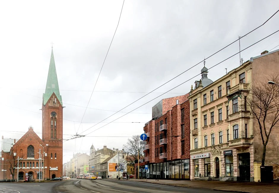 Street view featuring a historic red brick church with a tall green spire, modern buildings, and leafless trees on a cloudy day.