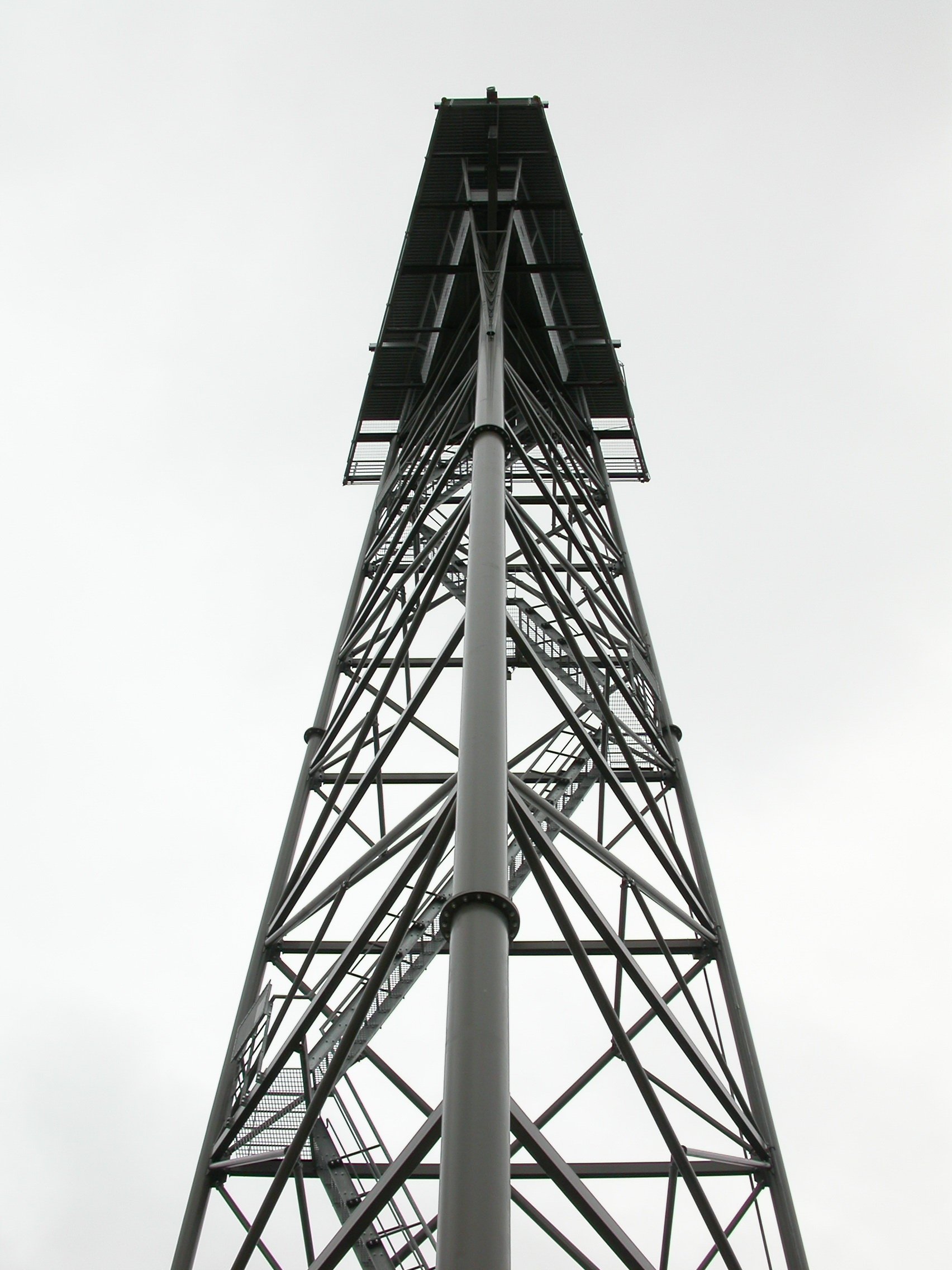 Low-angle view of a tall metal communication or radio tower against a cloudy sky.