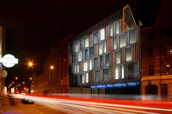 Night view of a modern building with illuminated windows and digital billboard showing advertisements, along a street with moving cars and streaks of light from their headlights and taillights.