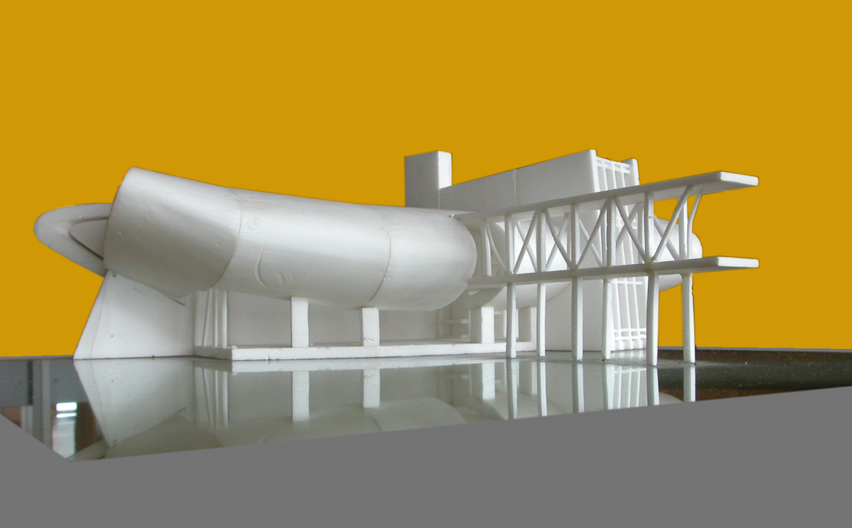 Architectural model of a modern building with a large horizontal rounded element, structural supports, and an extended rectangular section against a mustard yellow background.