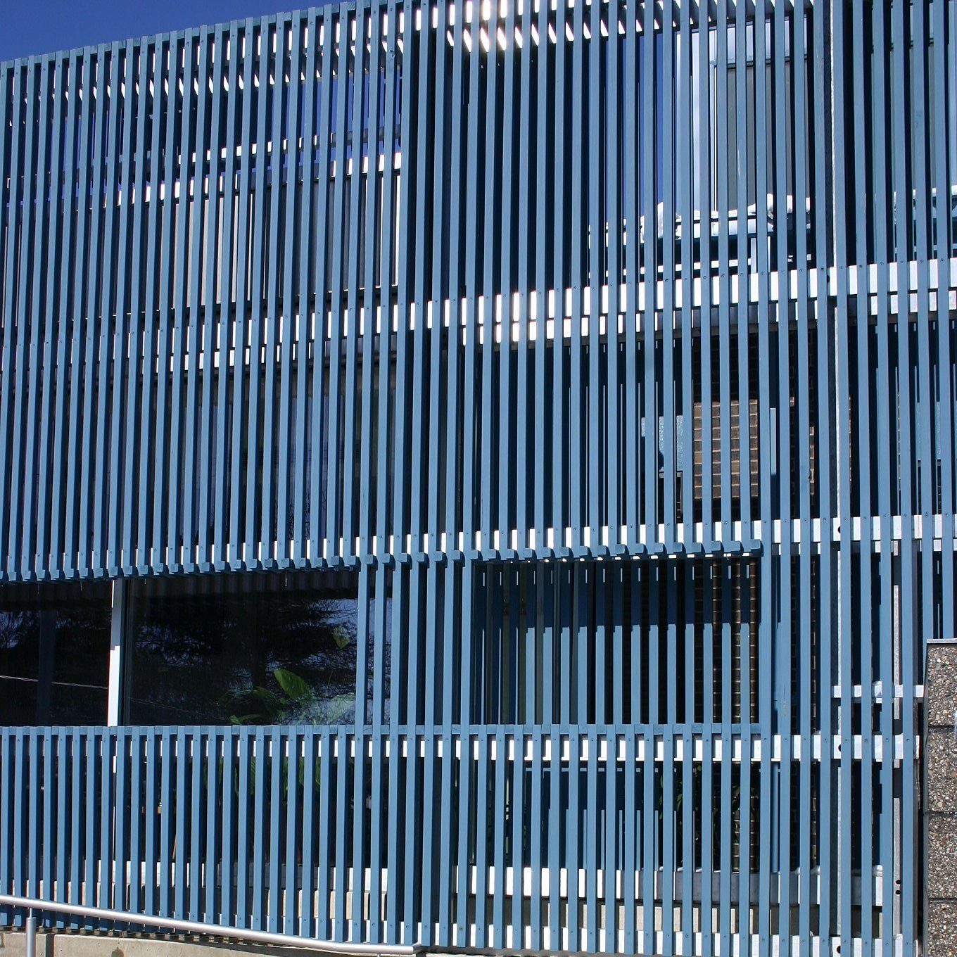 Modern building facade with vertical blue metal slats and glass windows
