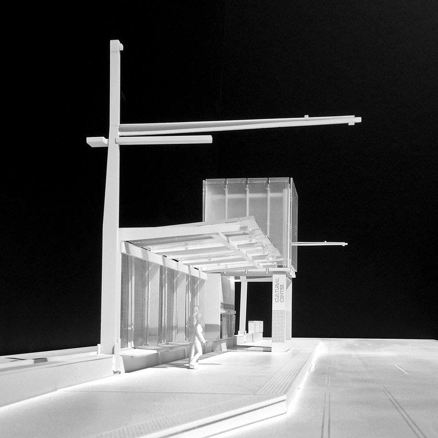 A white architectural model of a modern cultural center with a person walking near it, set against a black background.