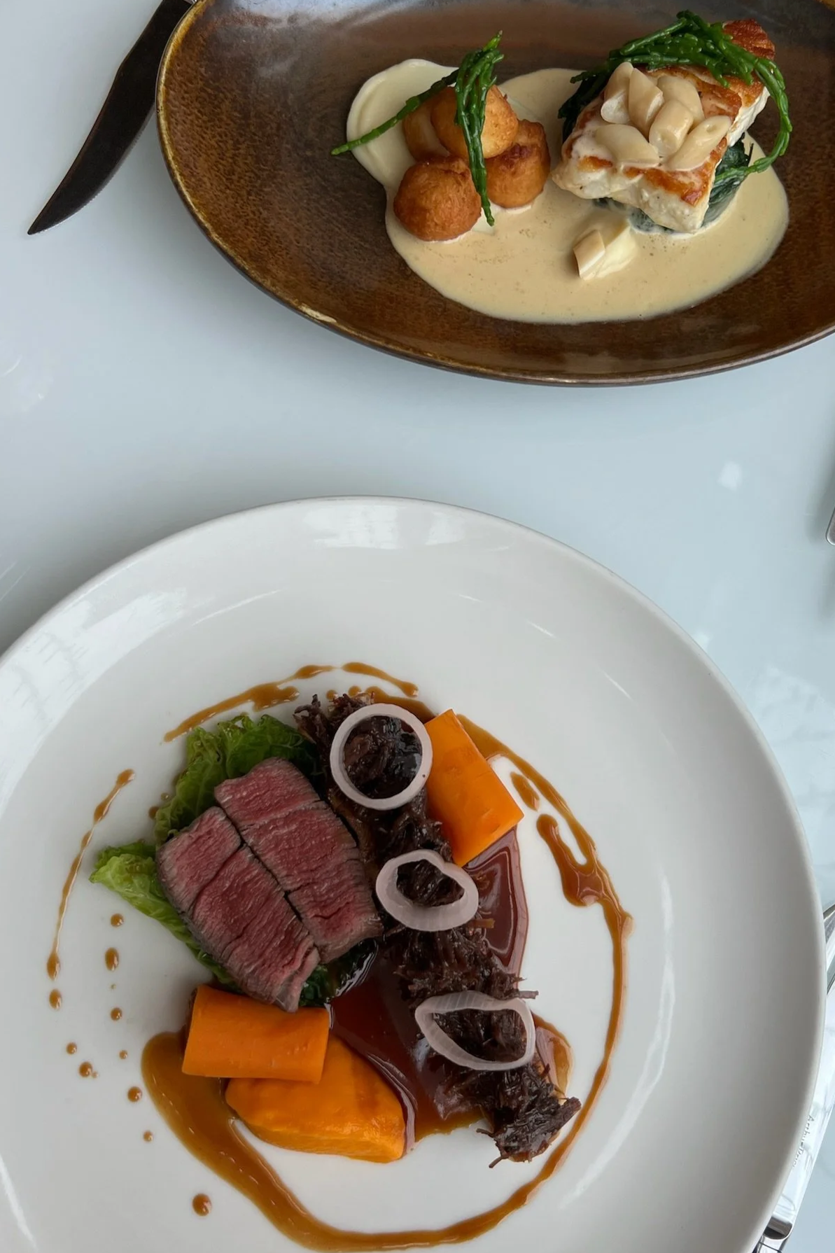 Luxury fine dining restaurant food photography featuring fish with creamy sauce and medium-rare steak, styled for social media content creation and hospitality marketing campaigns.