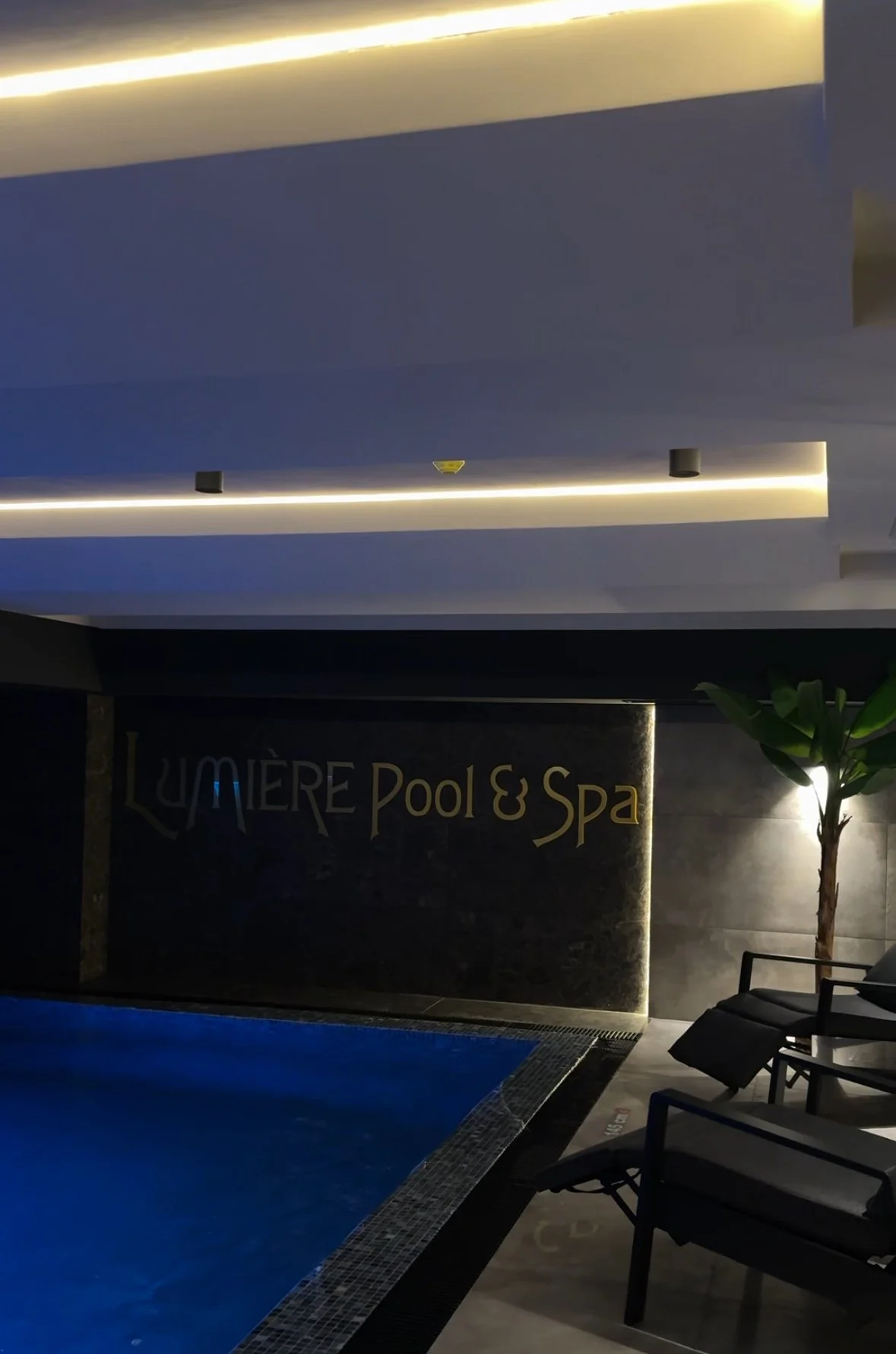 Modern luxury indoor pool and spa interior with ambient lighting and lounge seating, designed for hotel social media marketing and hospitality branding content.