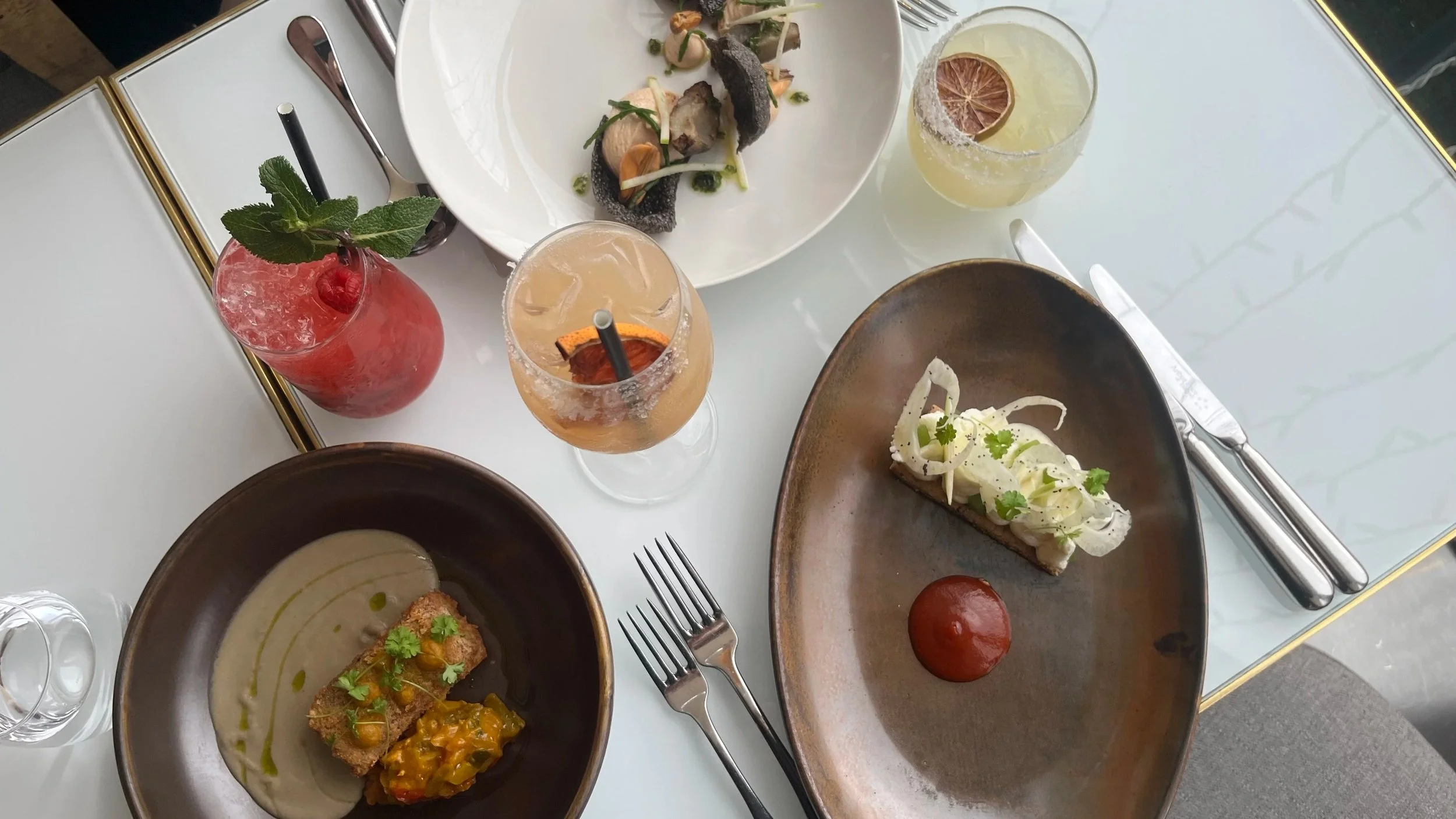 Luxury dining table featuring colourful cocktails and gourmet dishes, created for restaurant and bar social media content creation.