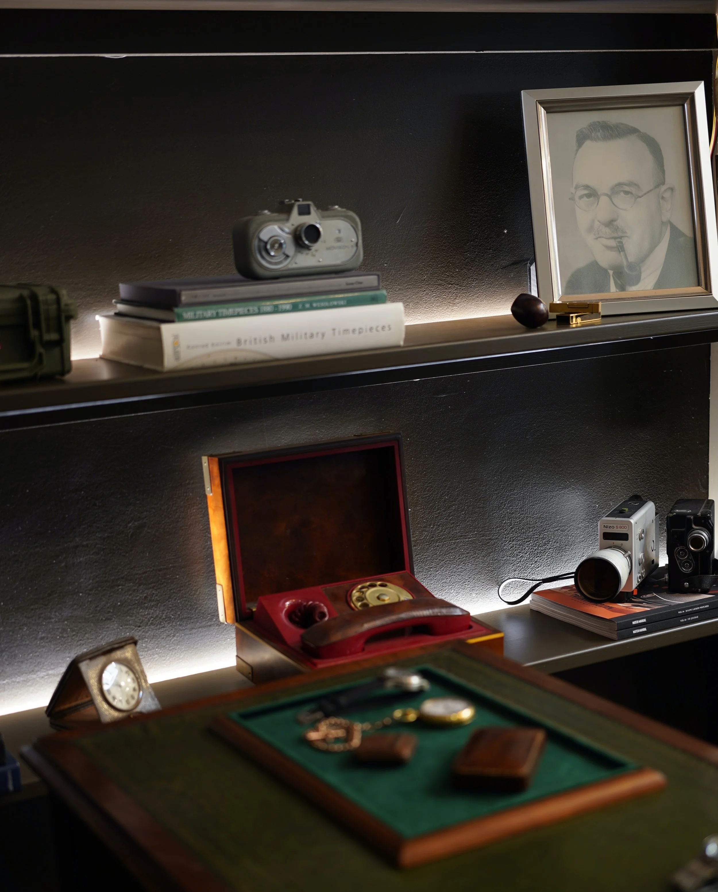 Shelf with vintage camera, books, framed photo of a man with glasses and pipe, and various vintage items.