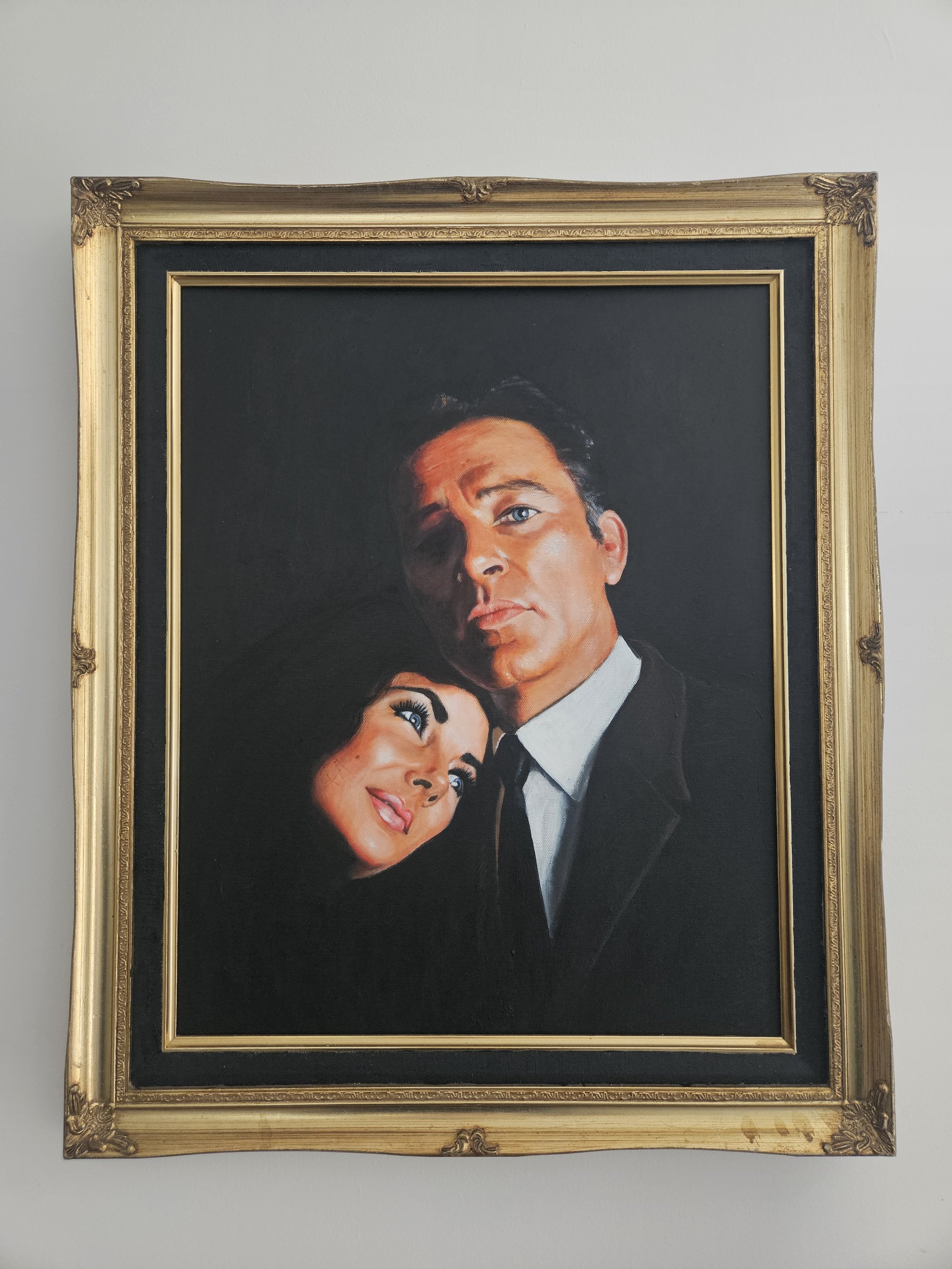 Elizabeth Taylor and Richard Burton. Hollywood.A framed painting of a man in a black suit and a woman with dark hair, wearing makeup, against a black background.