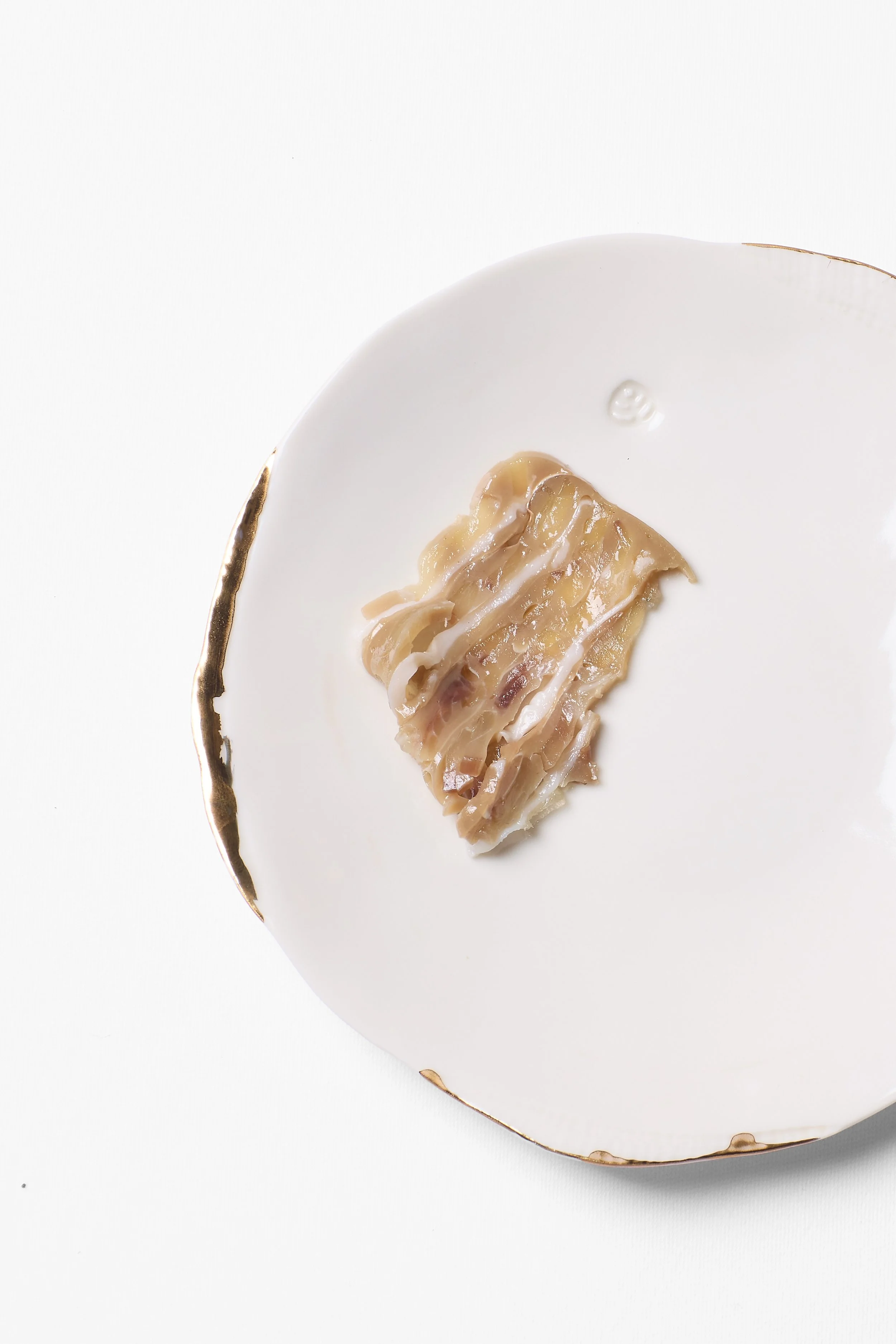 Une bouchée de dumpling posé sur une assiette blanche avec une bordure dorée.