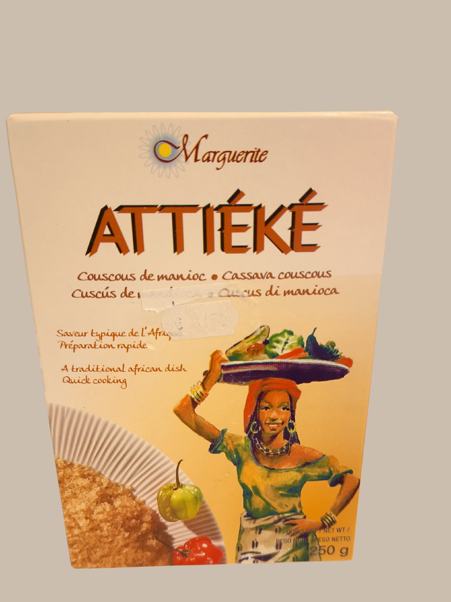 Une boîte d'Attiéké, un plat africain à base de couscous de manioc, avec une illustration d'une femme africaine portant un plateau de légumes sur la tête.