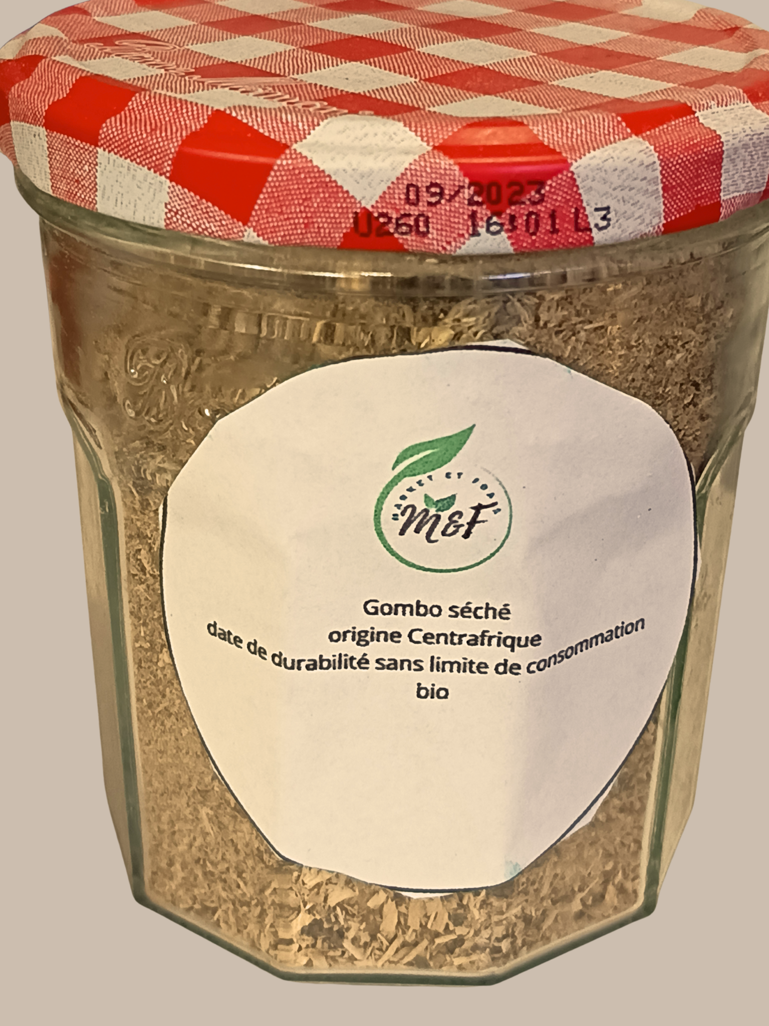 Pot de gombo séché bio d'origine Centrafrique, avec un couvercle en tissu à motif rouge et blanc.