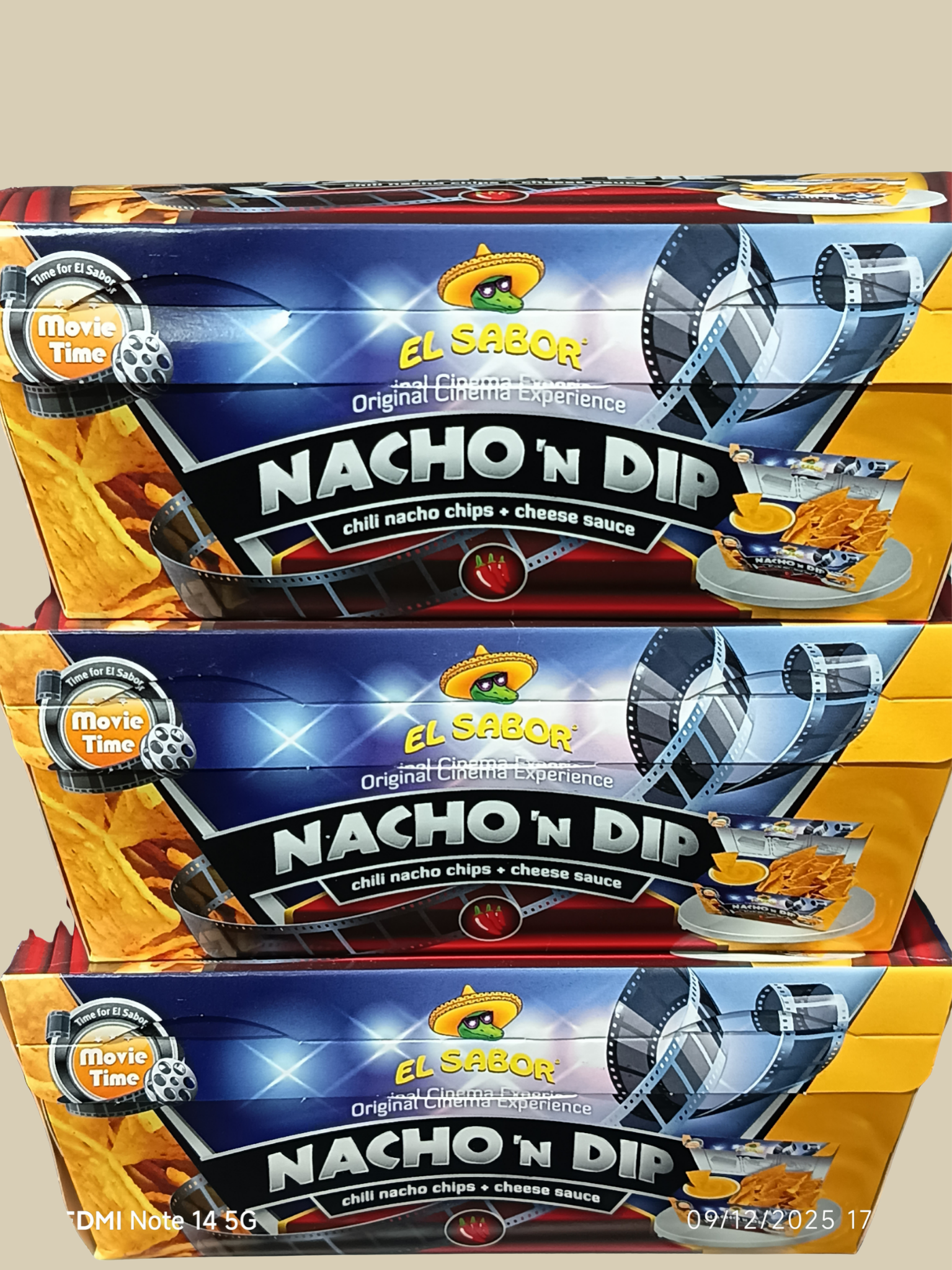Trois boîtes de chips Nacho n Dip saveur chili nacho et sauce au fromage, emballées en vue de face, avec des images de chips, sauce et un film de cinéma sur l'emballage.