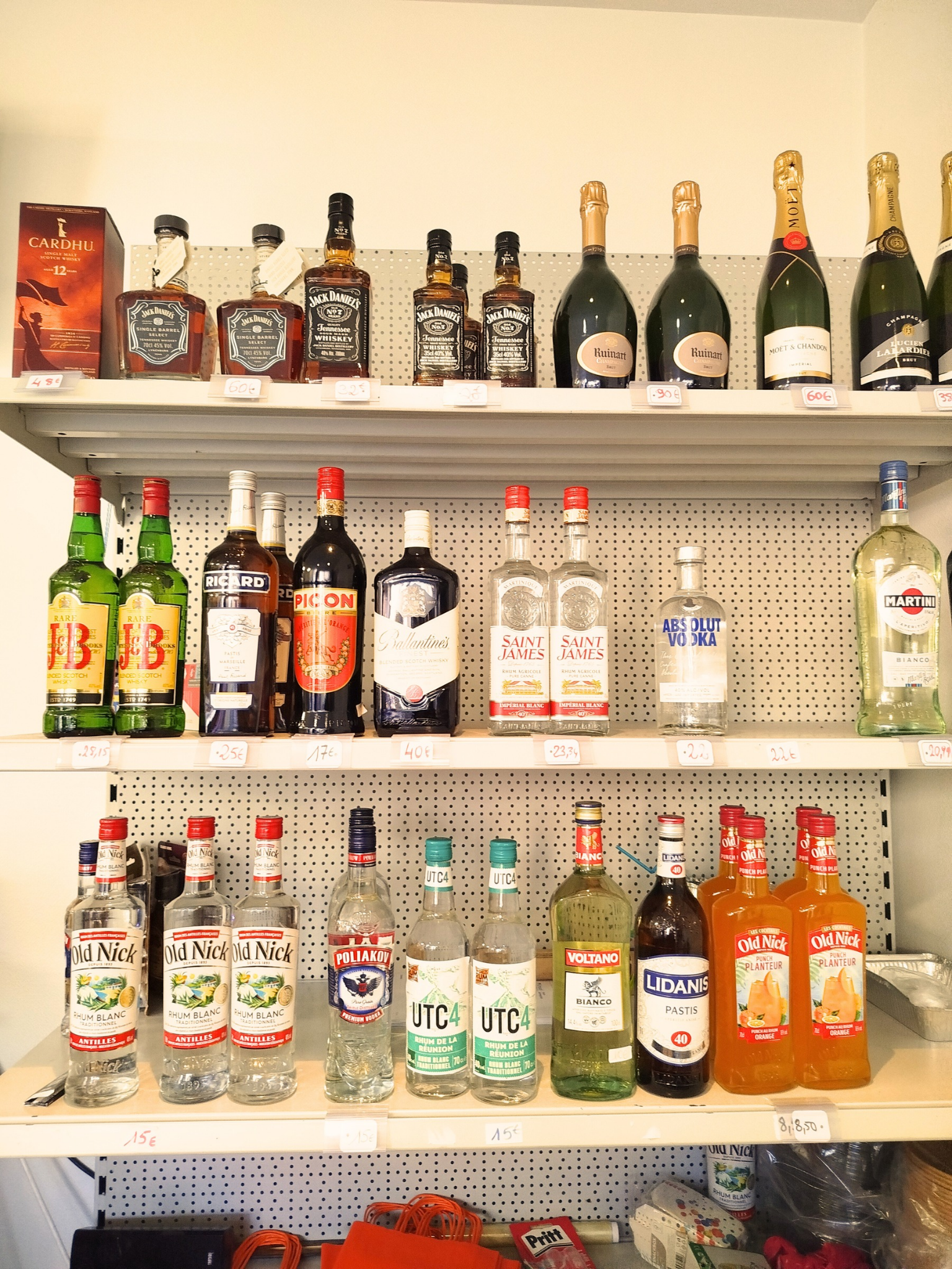 Rayonnage avec diverses bouteilles d'alcool, y compris du whisky, du champagne, de la vodka, du rhum, et des liqueurs, affichées en magasin.