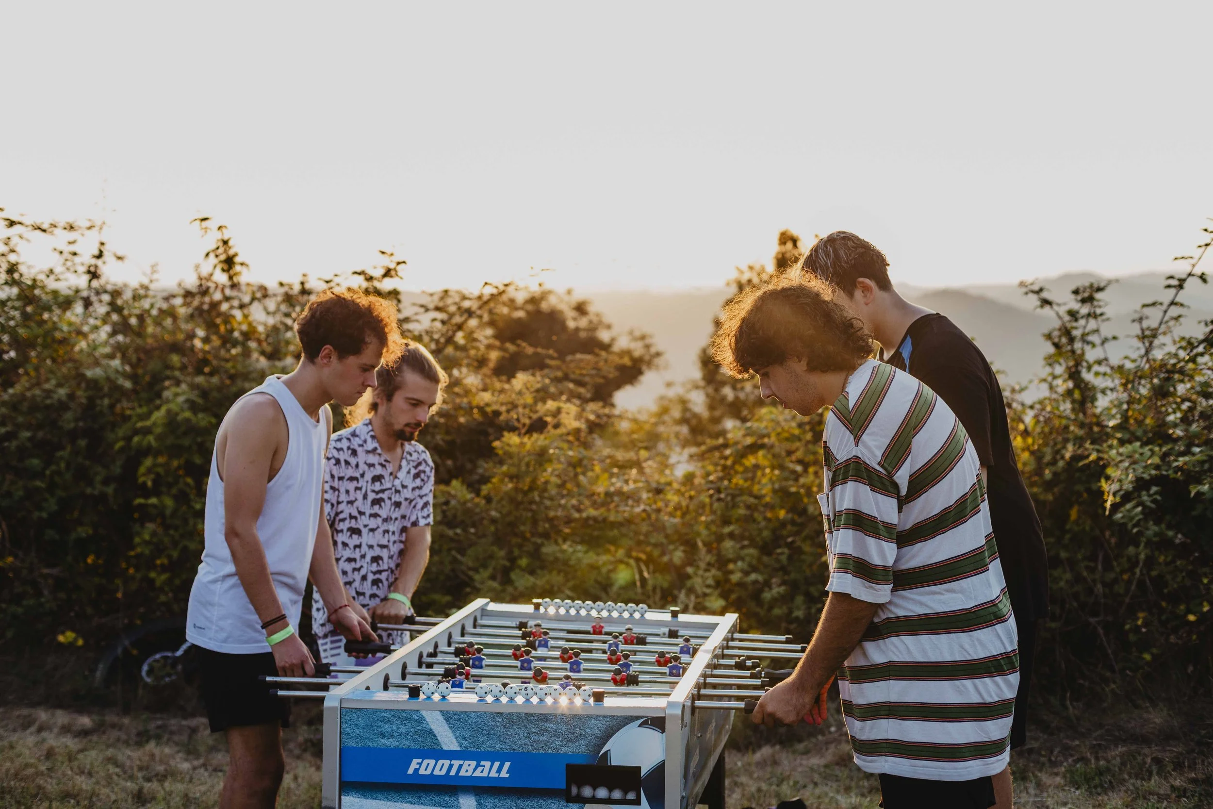 Giovani giocano a calcio balilla al tramonto durante ECOFestival a Bergolo