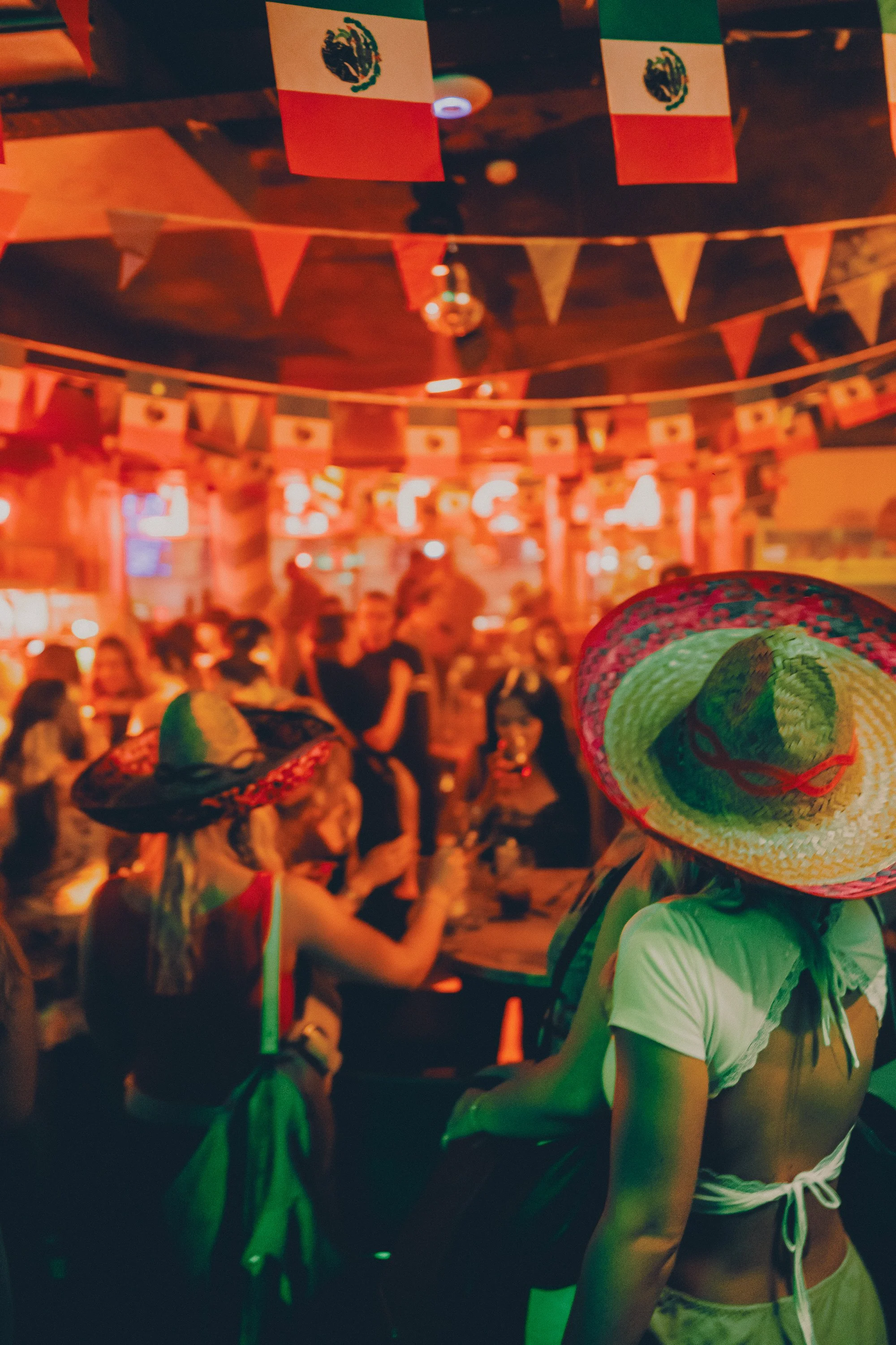 People celebrating a Mexican festivity decorated with Mexican flags and bunting, some wearing sombreros.