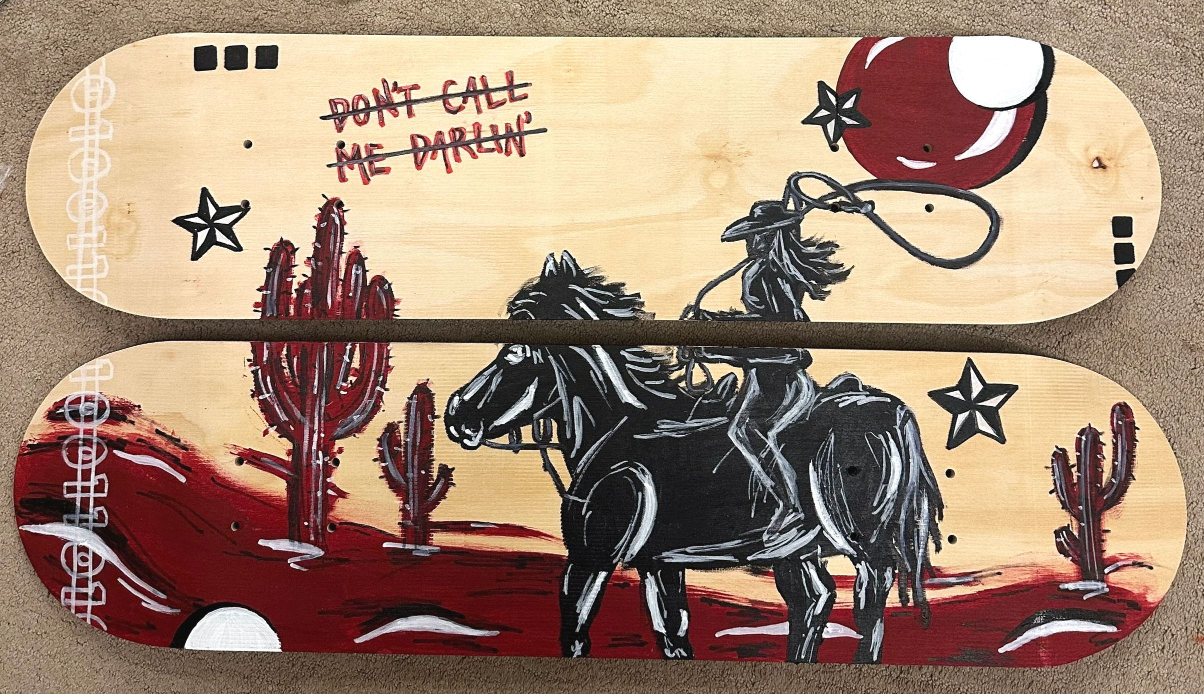 Skateboard deck with cowboy riding a horse, desert cacti, star graphics, and a crossed-out phrase 'Don't call me darling' on a wooden background.