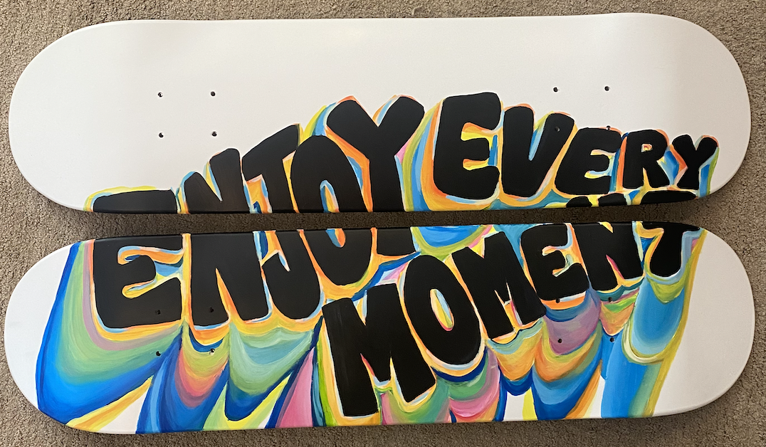 Two skateboard decks painted with the words 'Nothing Every' and 'Enthusiasm' in bold black letters surrounded by colorful swirls.