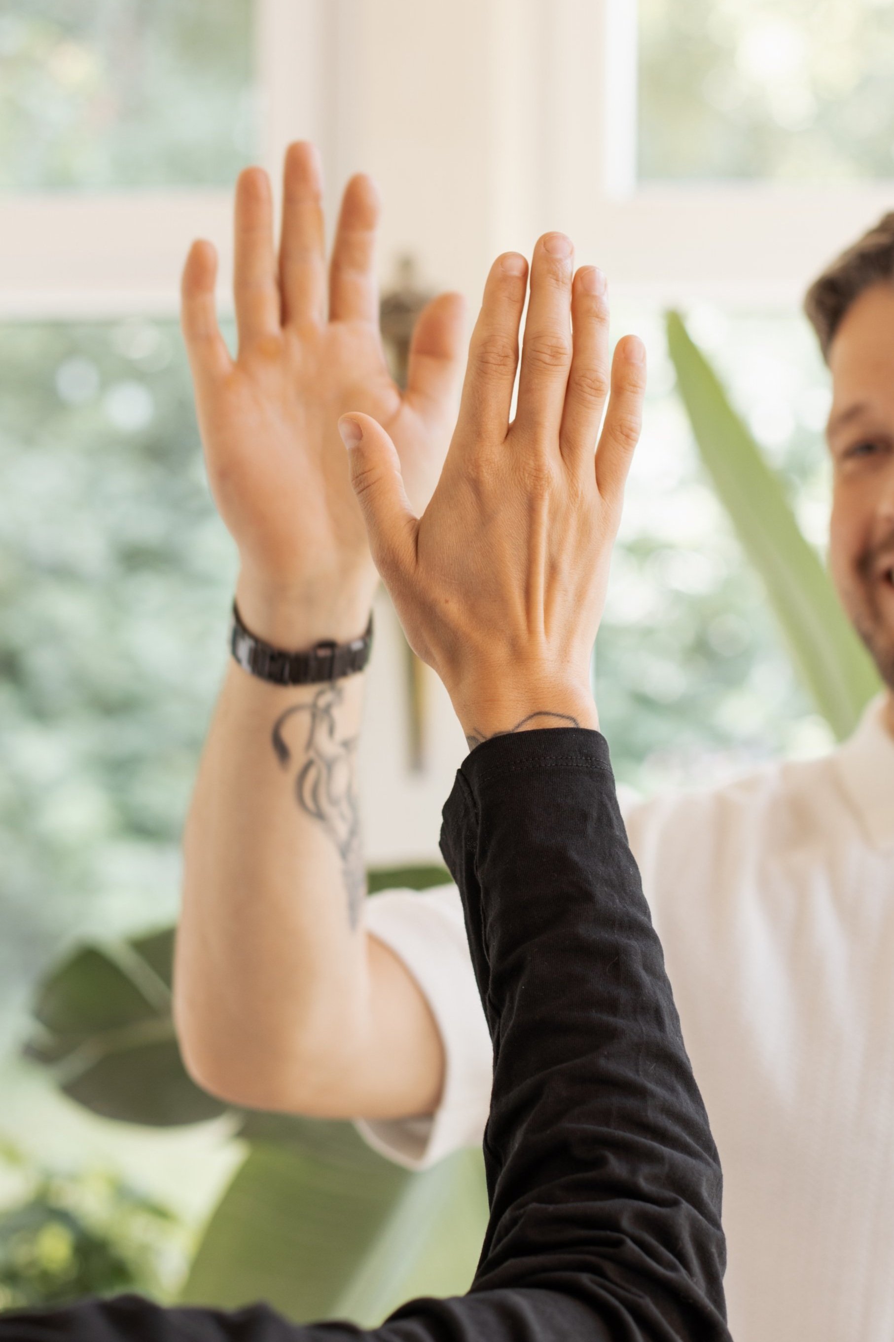 Zwei Personen machen ein High-Five in einem Raum mit viel natürlich Licht.