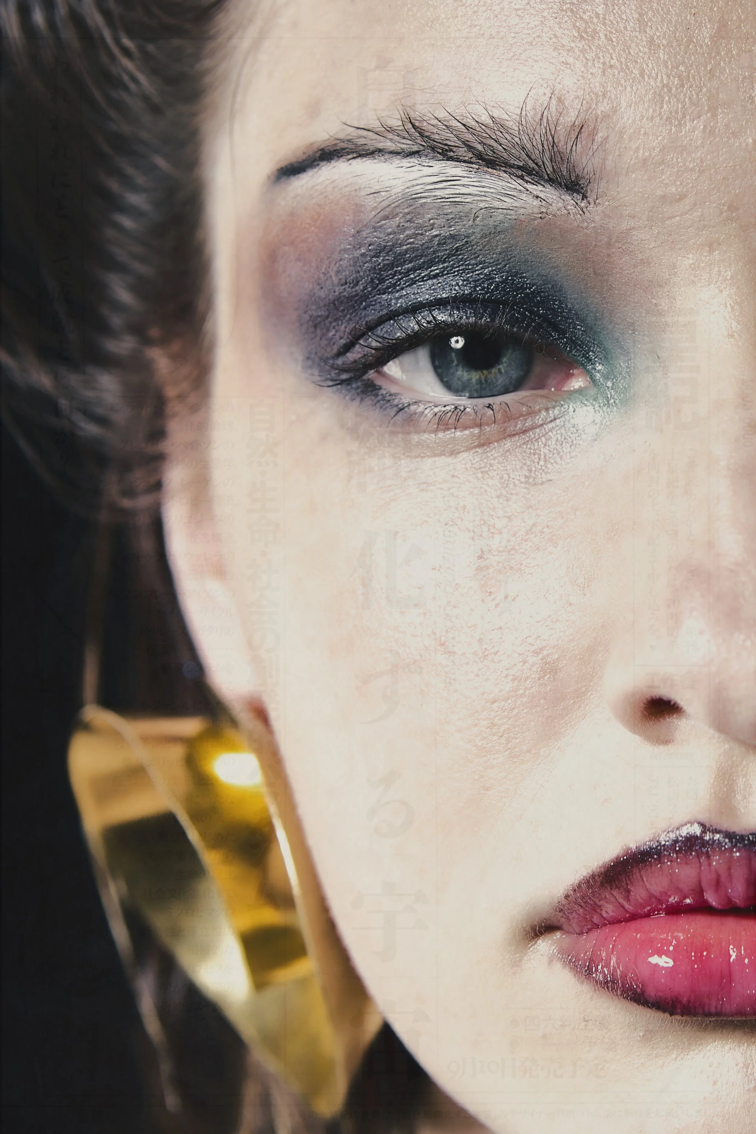 Primer plano de una mujer con maquillaje llamativo en el ojo, labios rosados y un pendiente grande dorado.