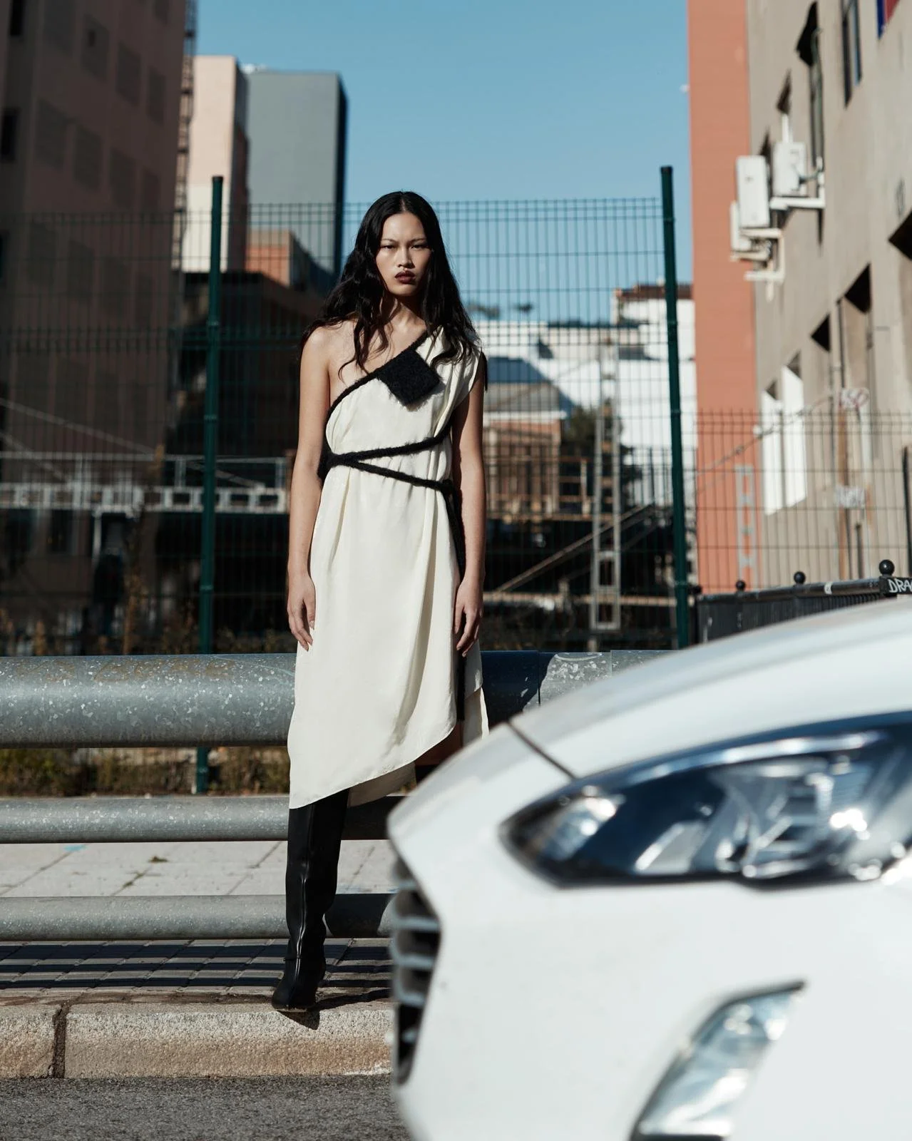Una mujer con vestido blanco y botas negras en una calle urbana