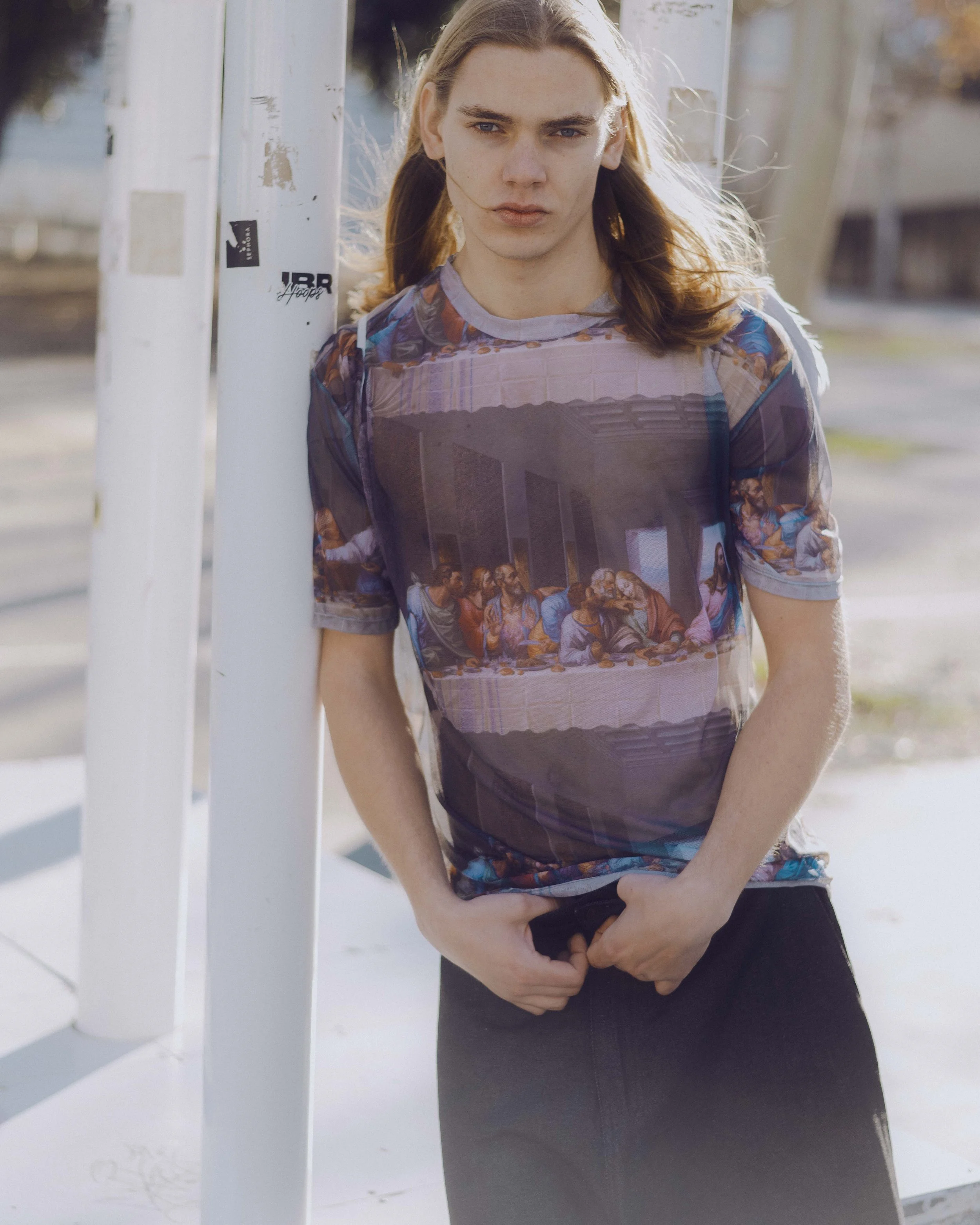 Joven con camiseta de 'La Última Cena' posando al aire libre en un día soleado.