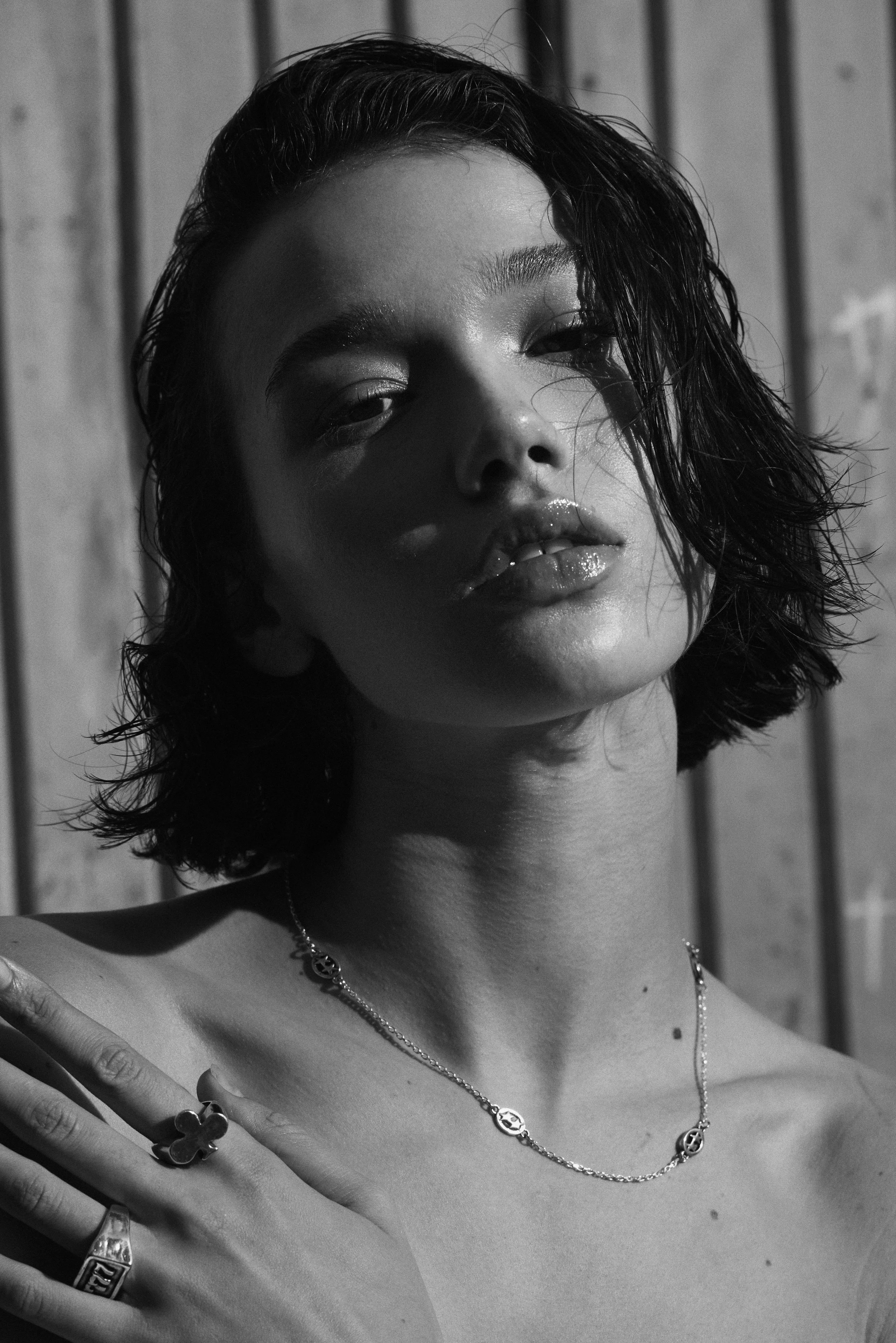 Retrato en blanco y negro de una mujer con cabello oscuro, solapada, con accesorios y expresión pensativa.