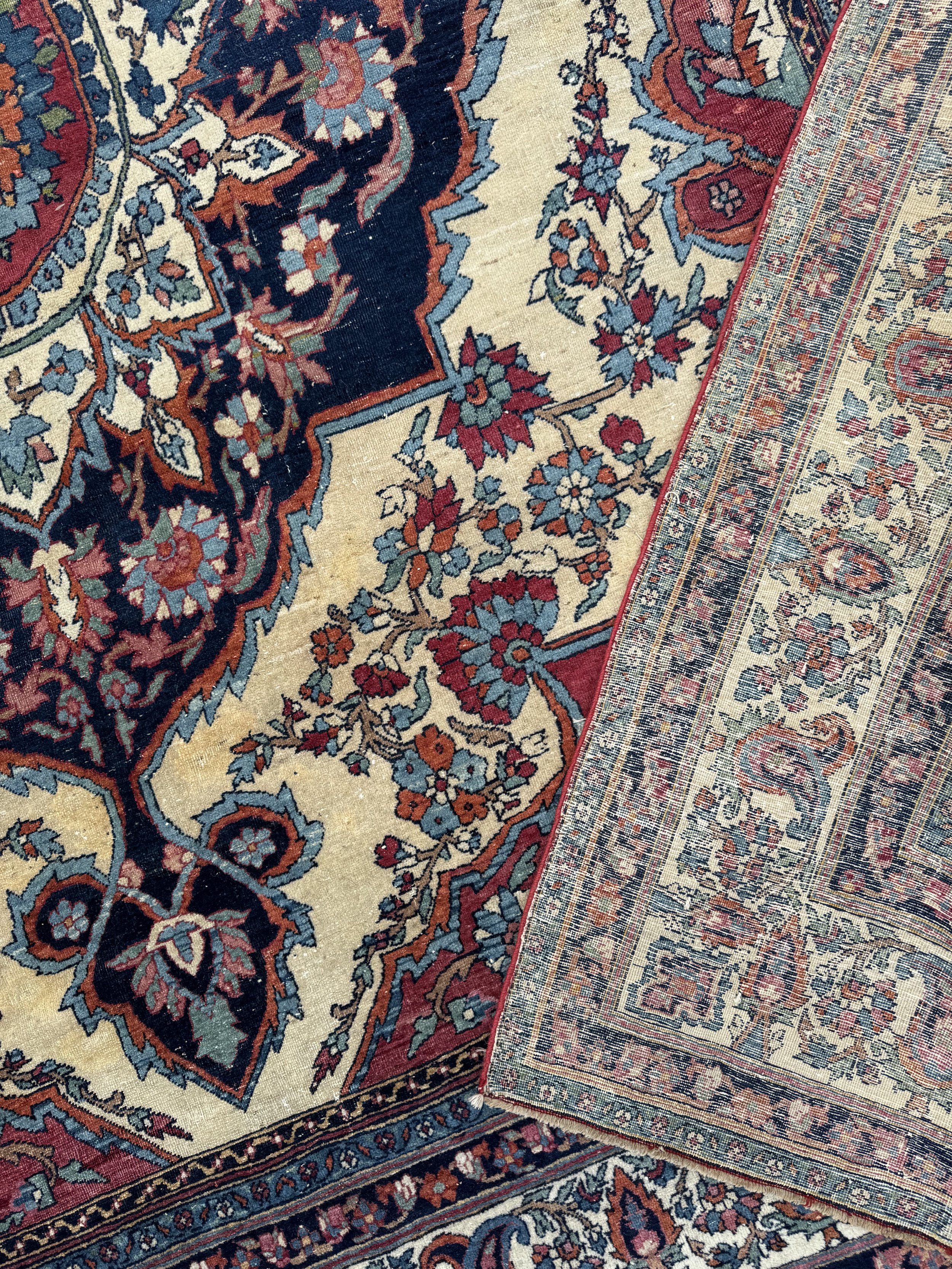 Close-up of a traditional Persian-style area rug with intricate floral patterns in red, blue, and beige colors.