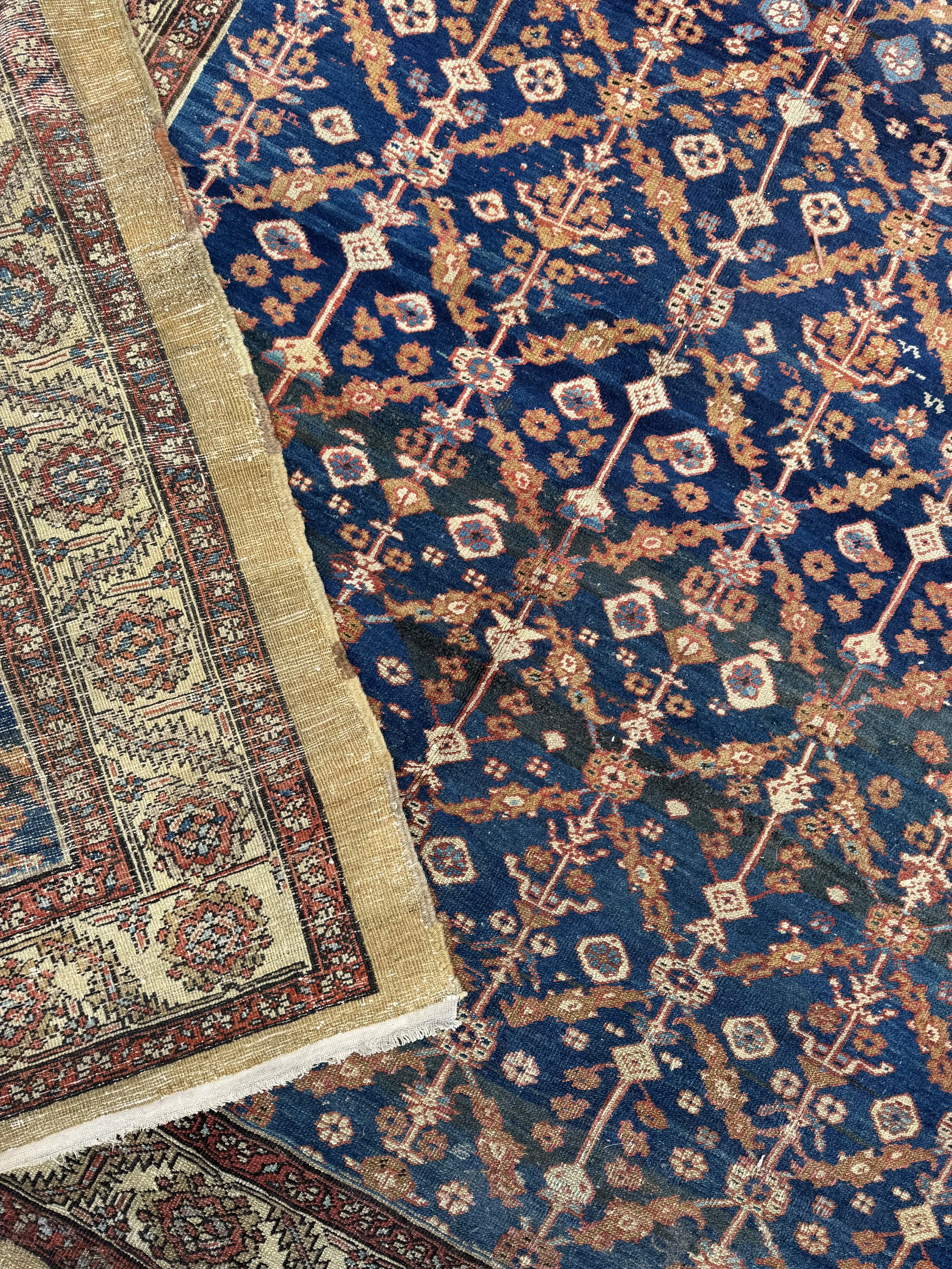 Close-up of intertwined Persian-style rugs with ornate floral and geometric patterns in colors of blue, red, black, and cream.