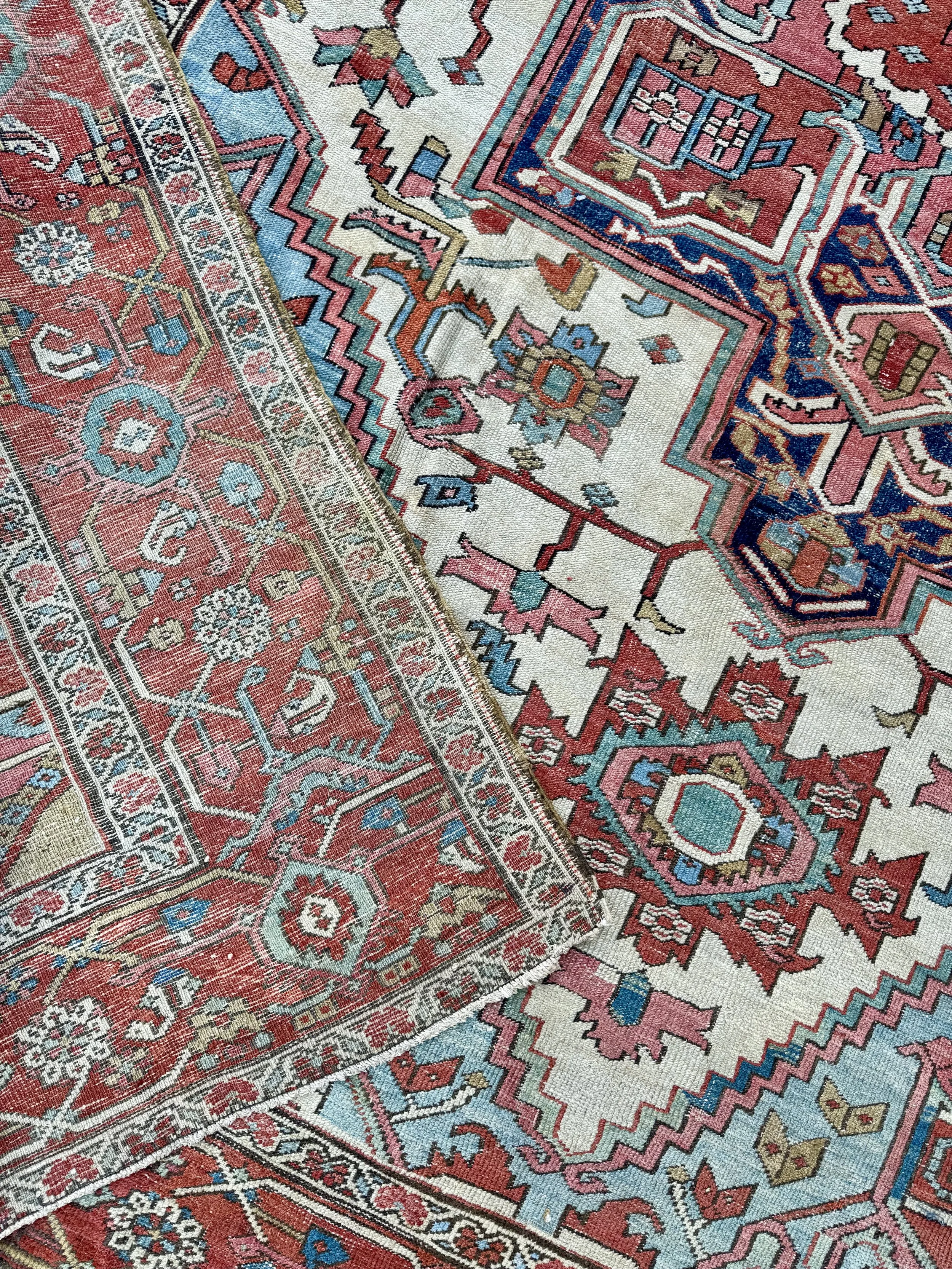 Close-up of a colorful Persian-style woven rug with intricate geometric patterns in shades of red, blue, beige, and pink.