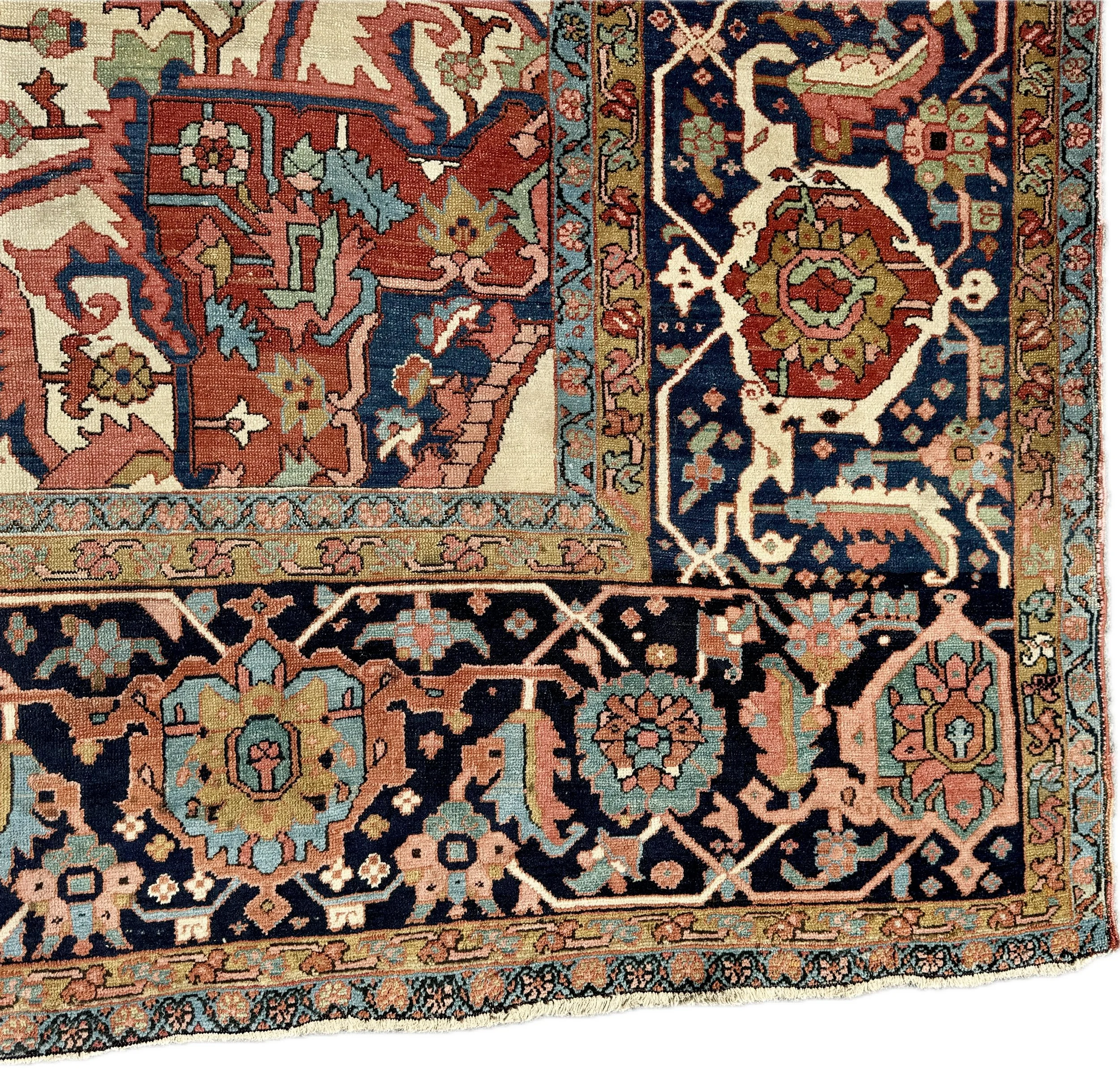 Close-up of a traditional Persian-style rug with intricate floral and geometric patterns in navy blue, red, pink, light blue, white, and beige colors.