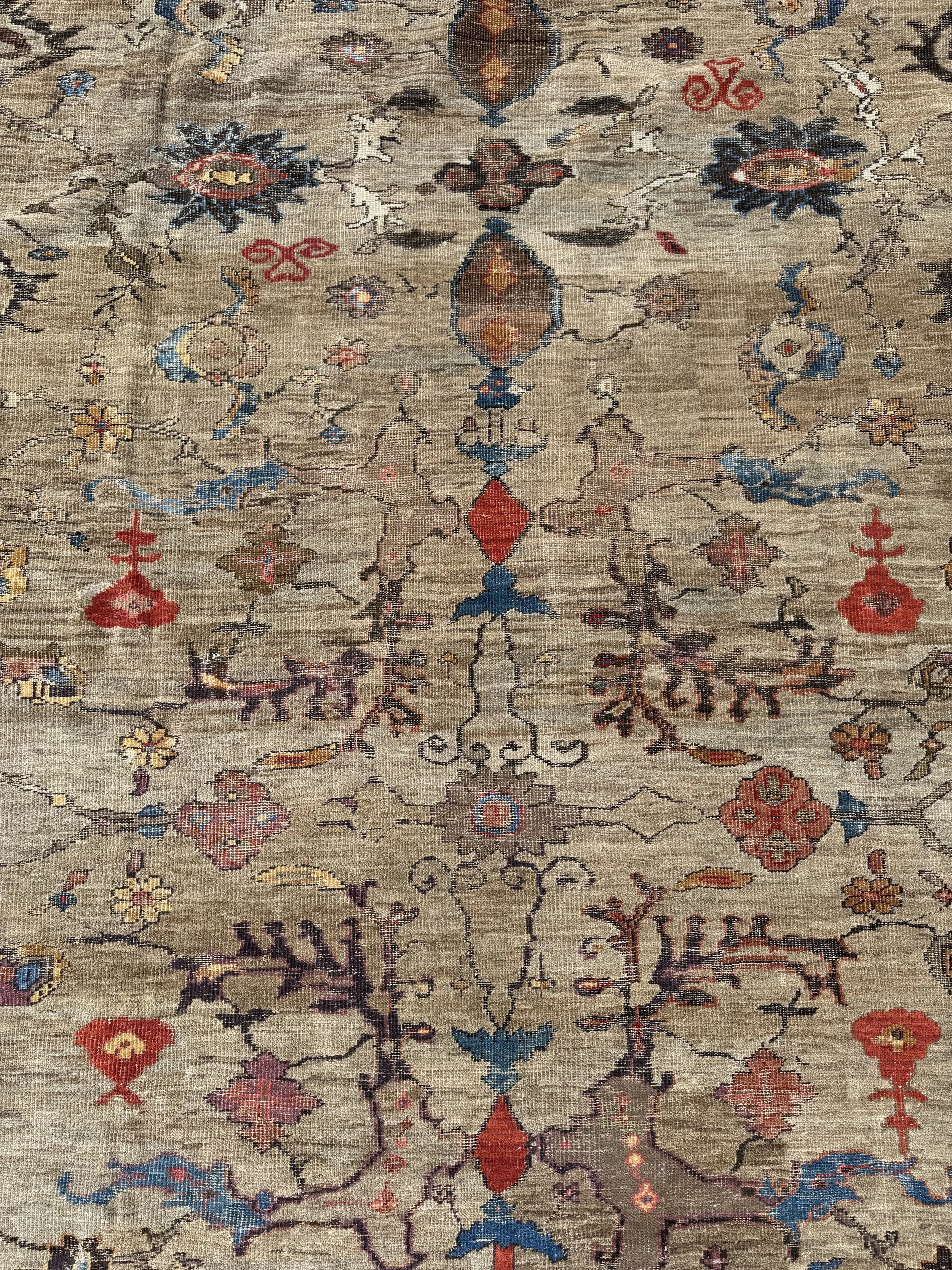 A detailed view of a vintage Persian-style rug with intricate floral and geometric patterns in shades of blue, red, yellow, and beige.