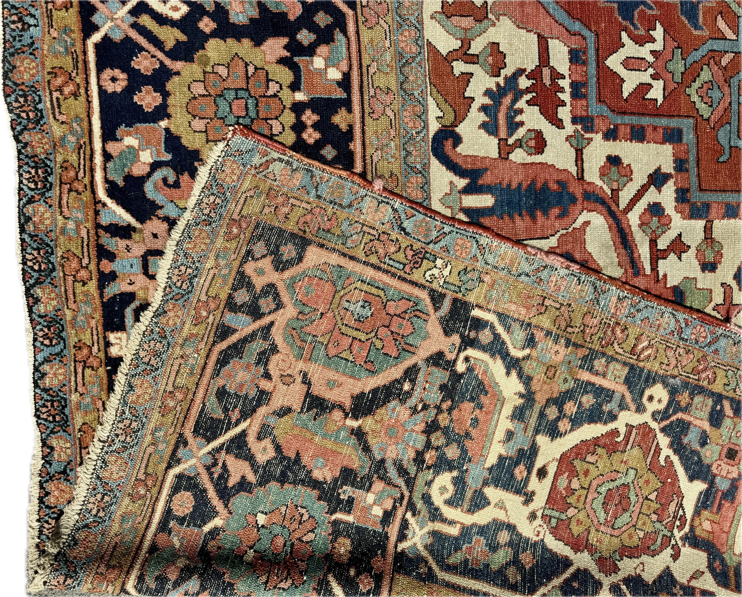 Close-up of a traditional patterned rug featuring floral and geometric designs in shades of black, red, green, beige, and pink.