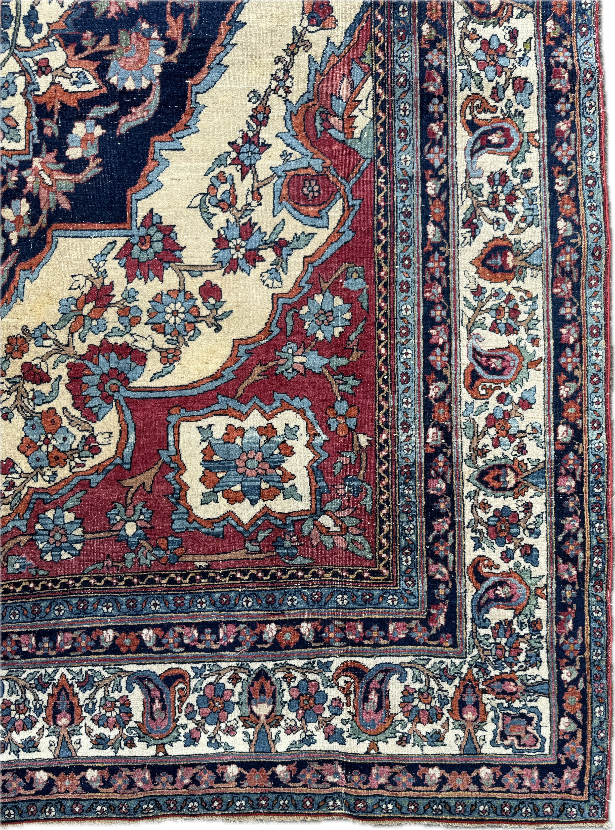 A detailed section of a traditional Persian-style woven rug featuring intricate floral and geometric patterns in shades of red, cream, blue, black, and beige.