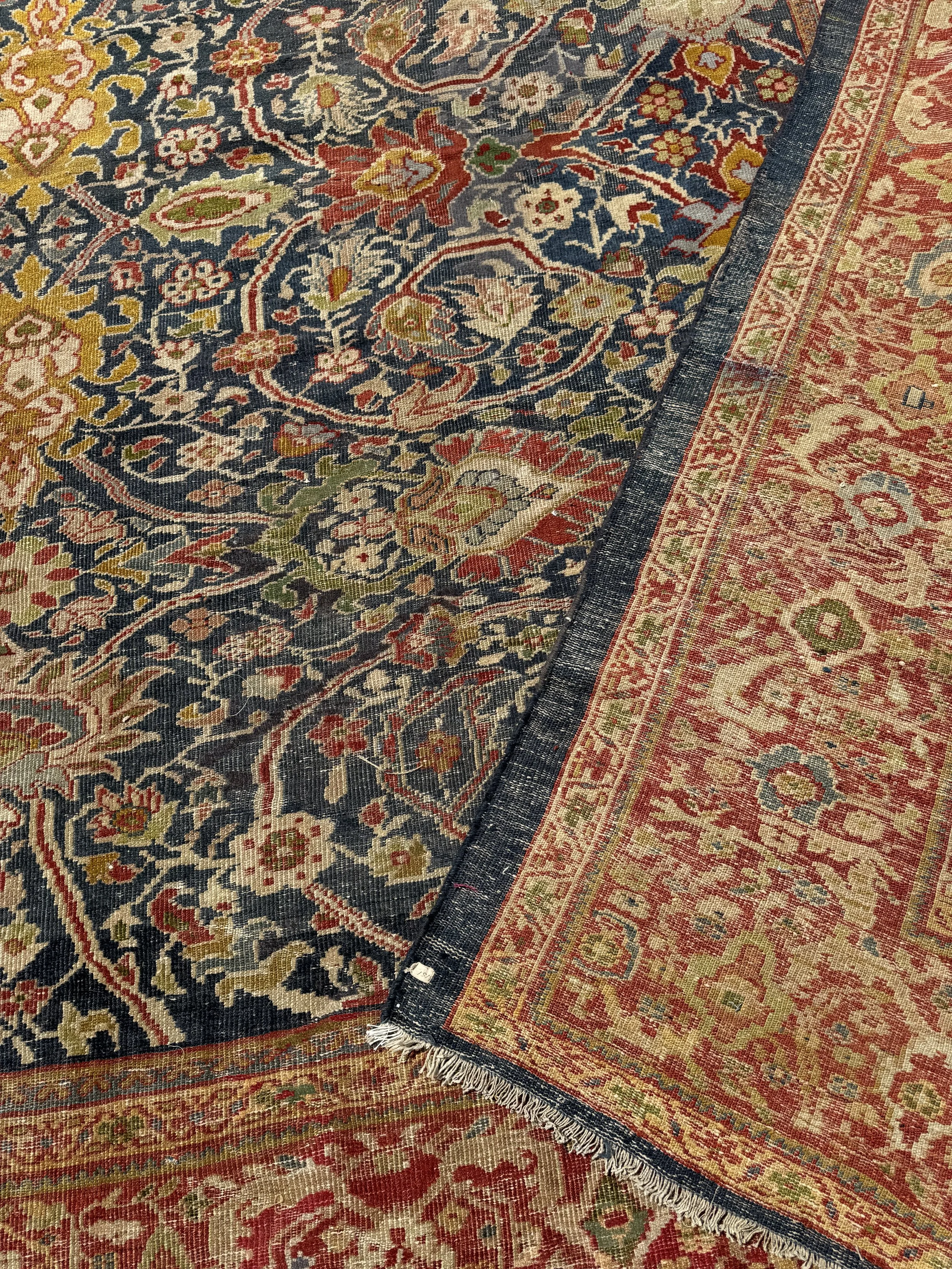 Close-up of two overlapping traditional oriental rugs with intricate floral and geometric patterns in red, navy, beige, and green colors.