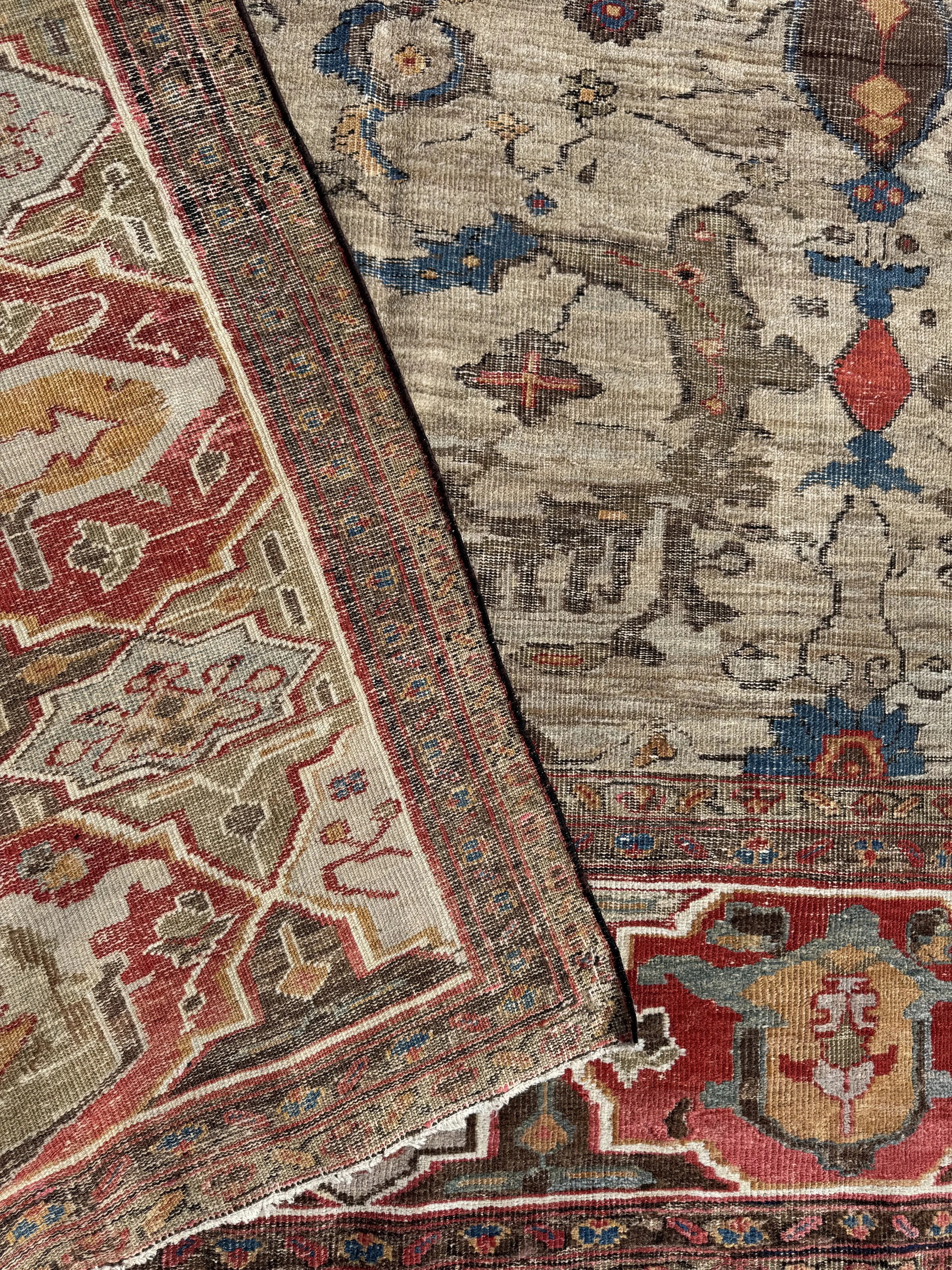 Close-up of two overlapping vintage area rugs with intricate traditional patterns and colors including red, blue, gold, and beige.