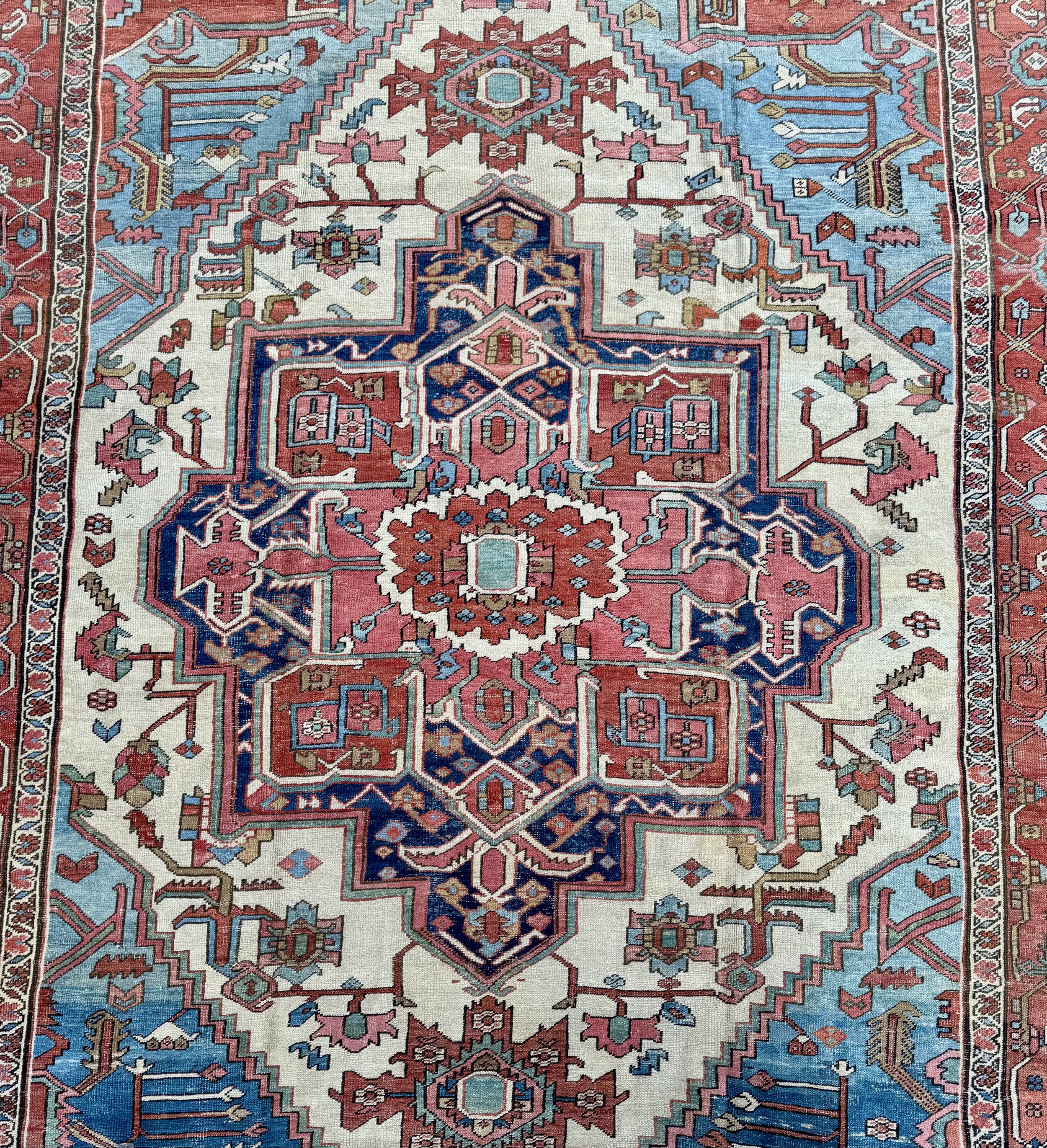 Colorful Persian-style rug with intricate geometric and floral patterns in red, blue, pink, and cream colors.